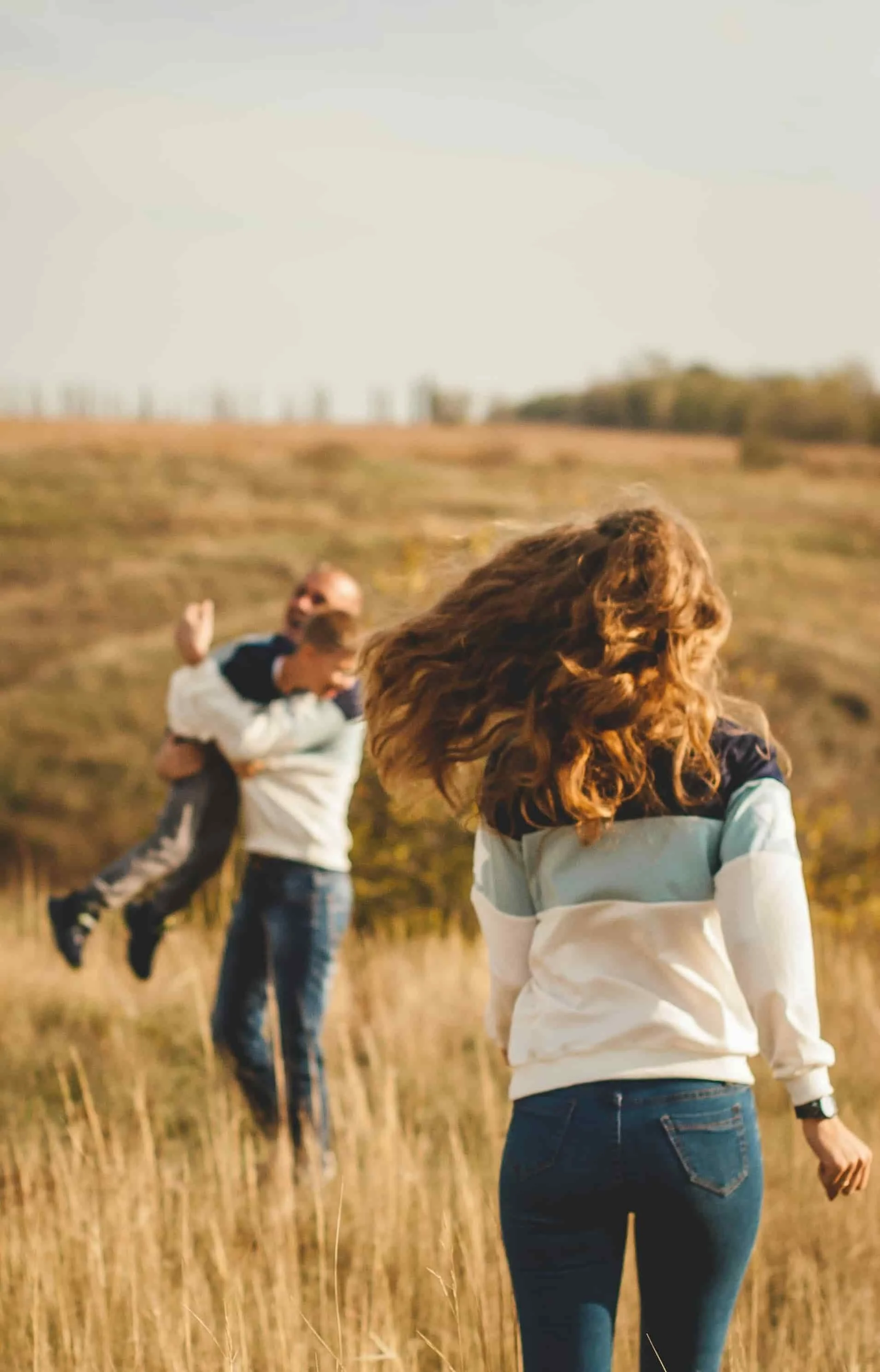 mom running towards dad and son playing field