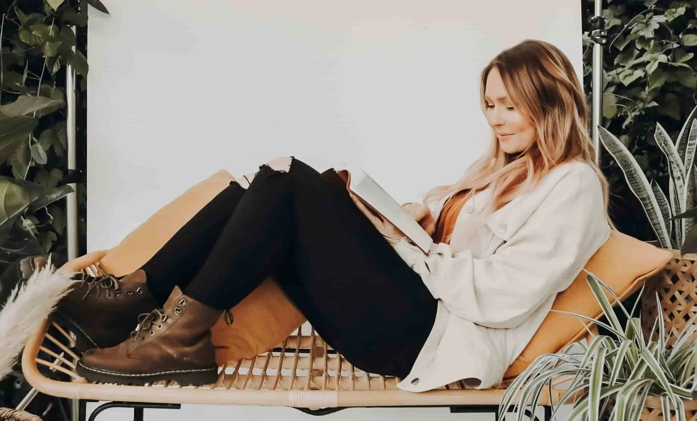 girl laying on bench while reading book
