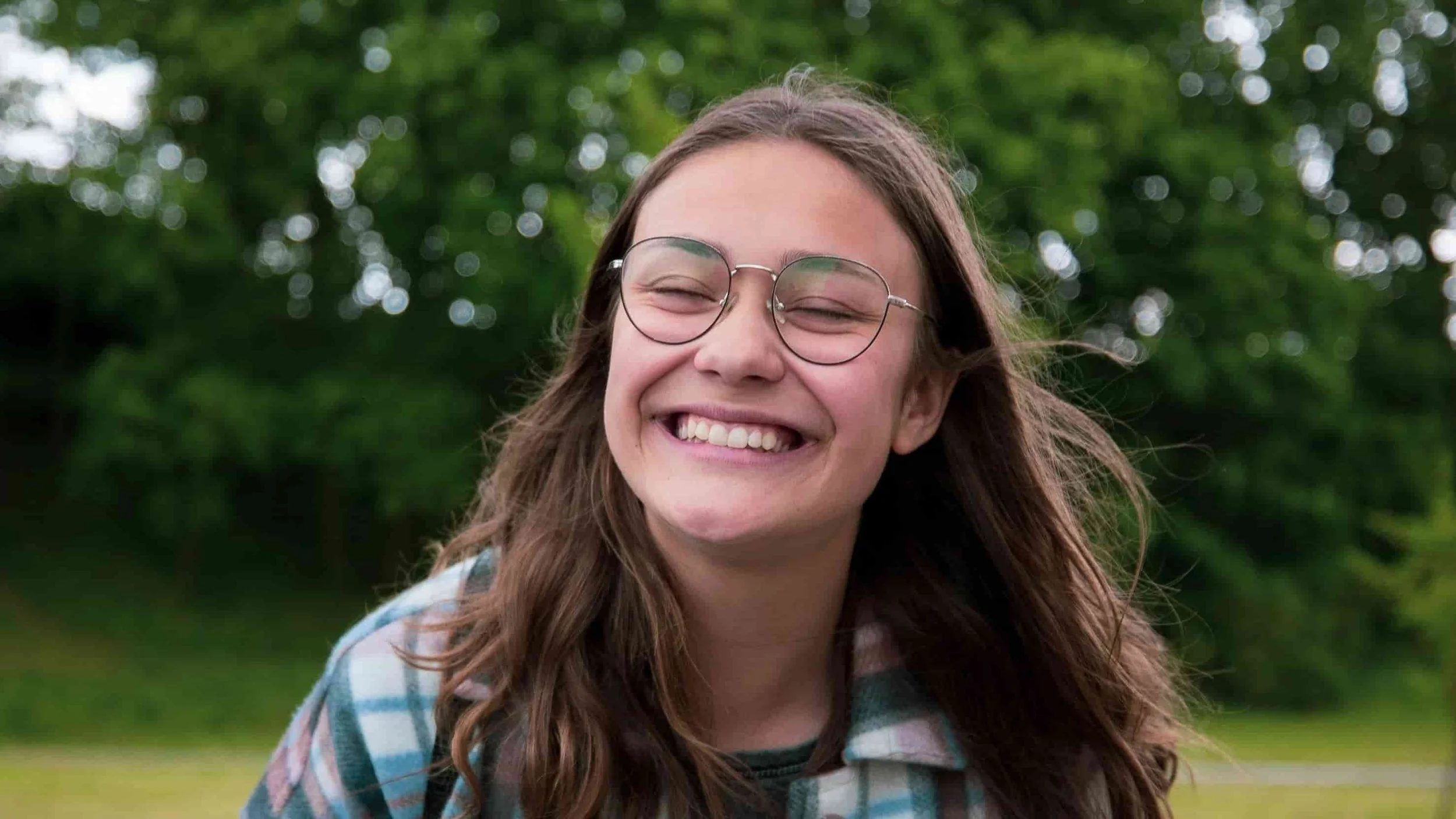 teen girl smiling at camera with eyes closed