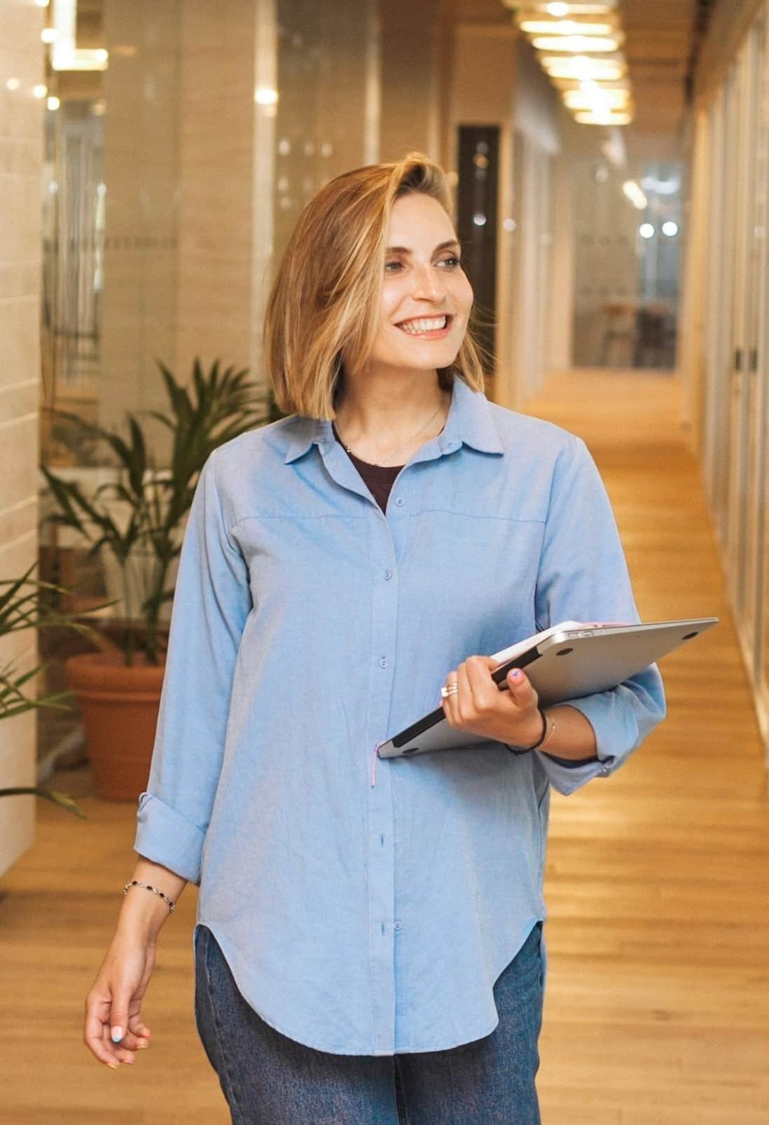 woman walking in office with laptop in hand