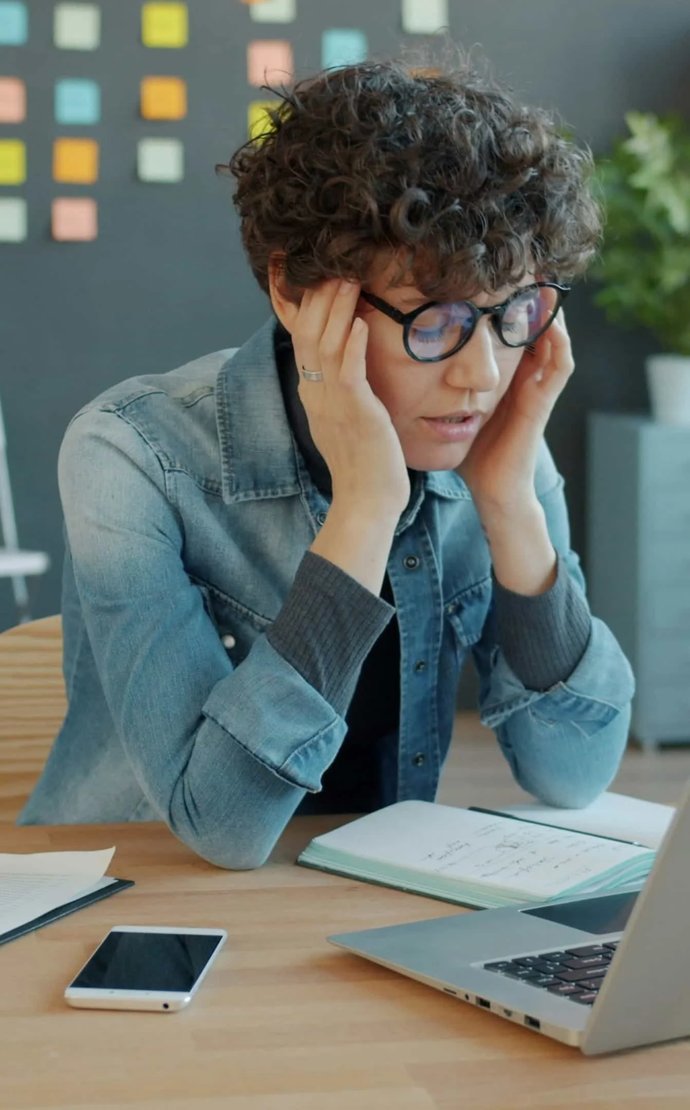 woman closing eyes with head in hands trying to relieve headache at work