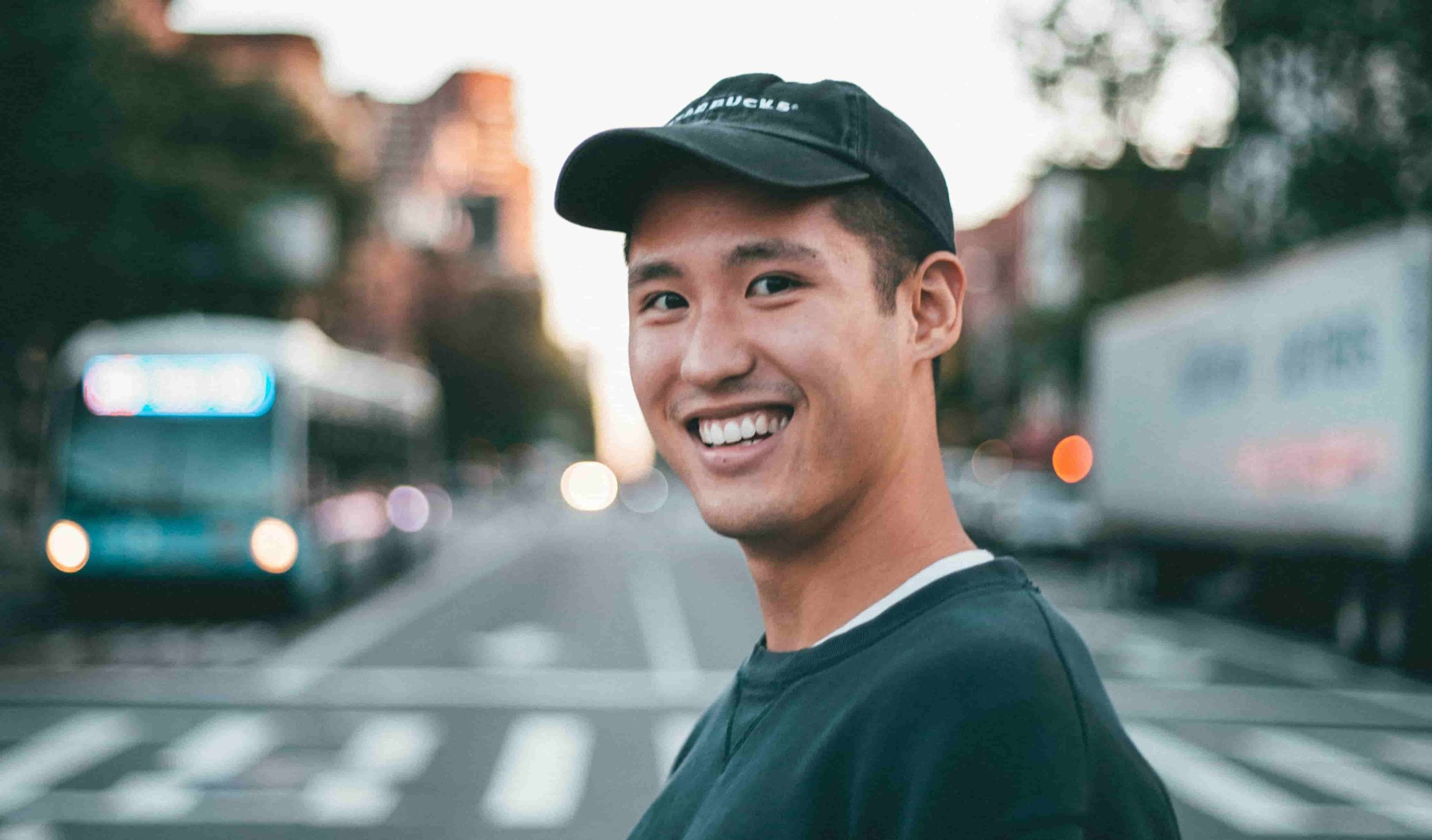 man smiling at camera while crossing the road