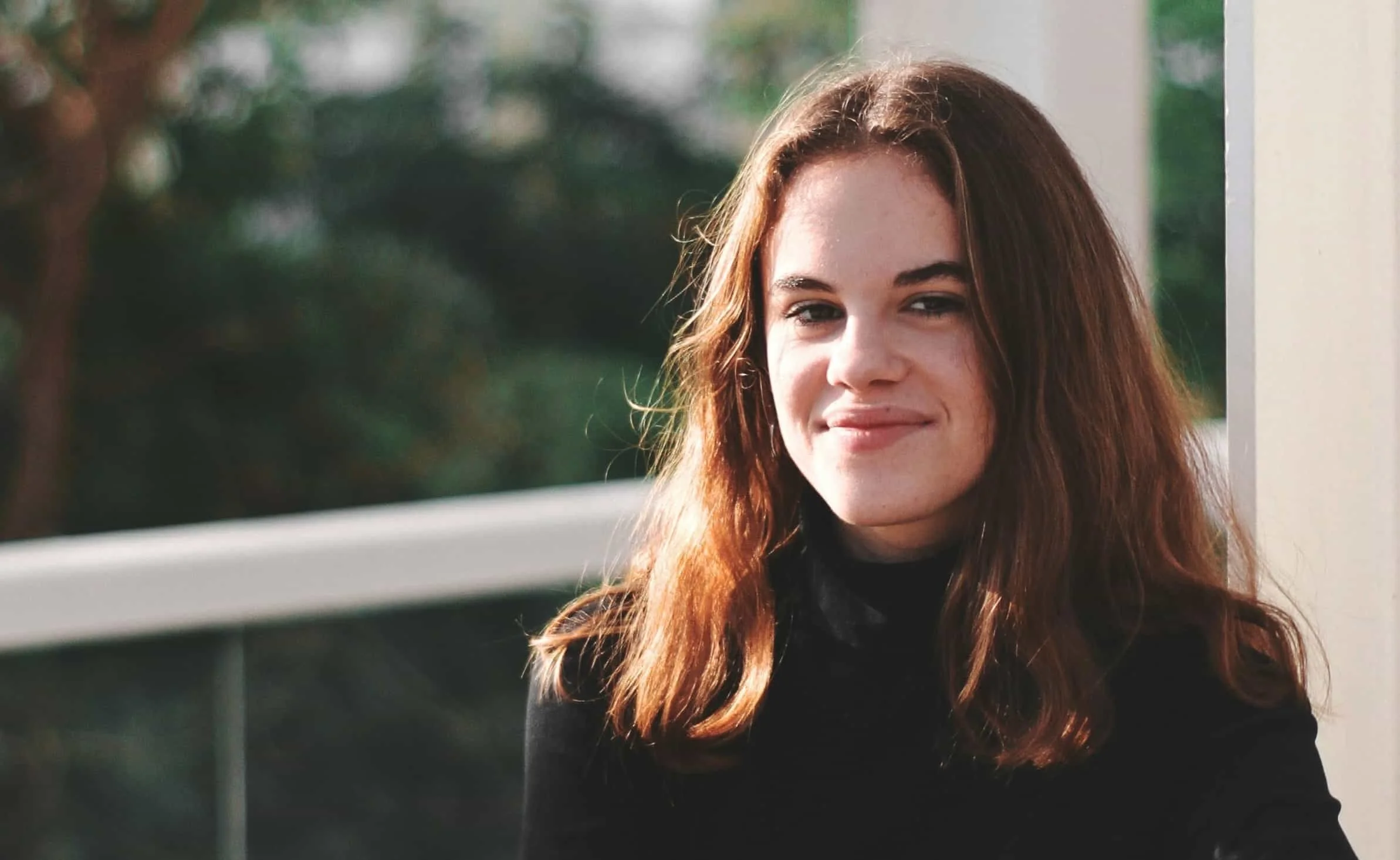 teen girl leaning on railing and smiling