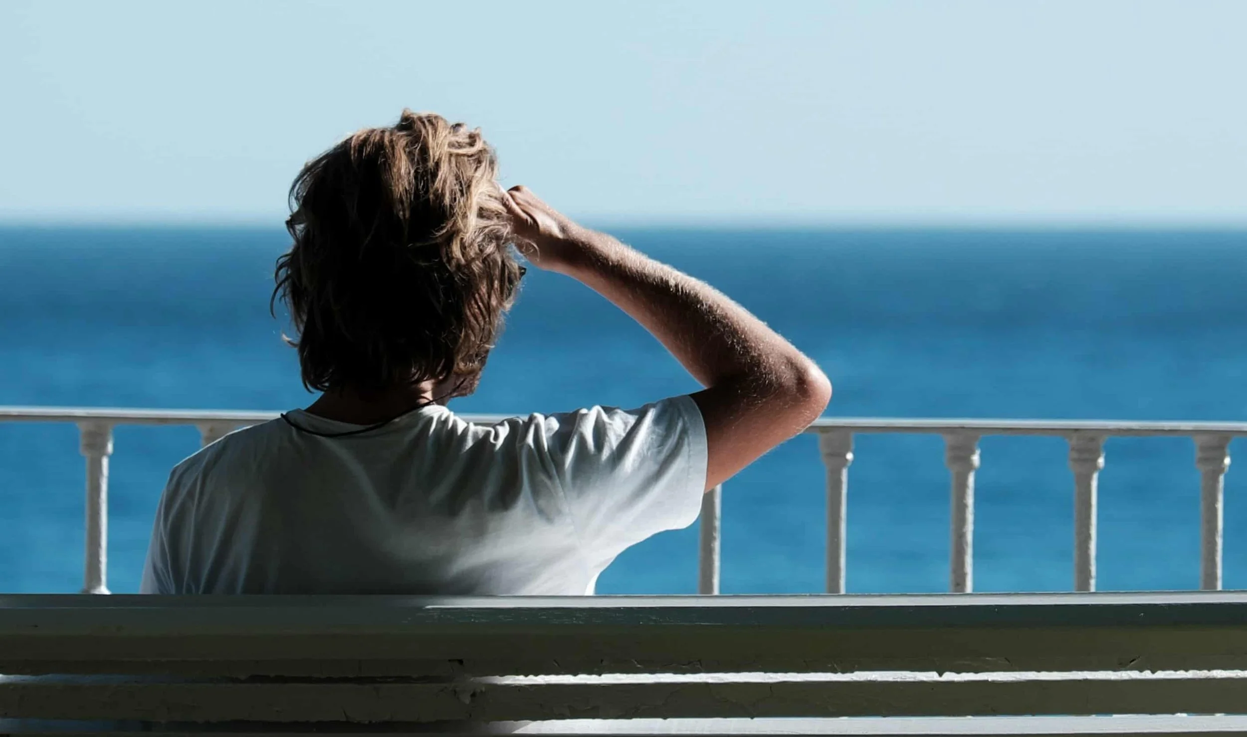 man sitting on bench in front of lake