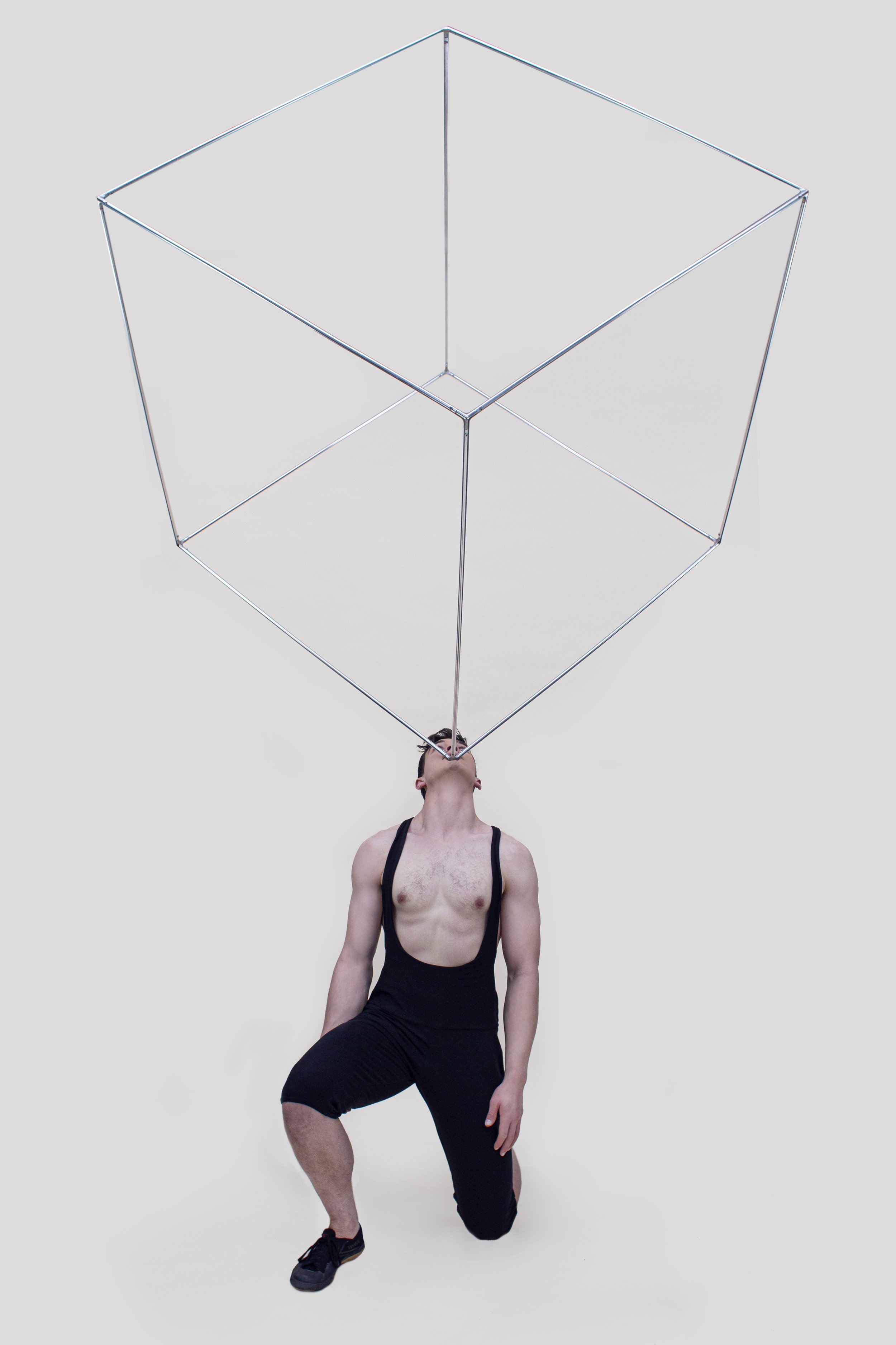 Mike Corr Circus balances a giant metal cube on his chin during a performance photoshoot