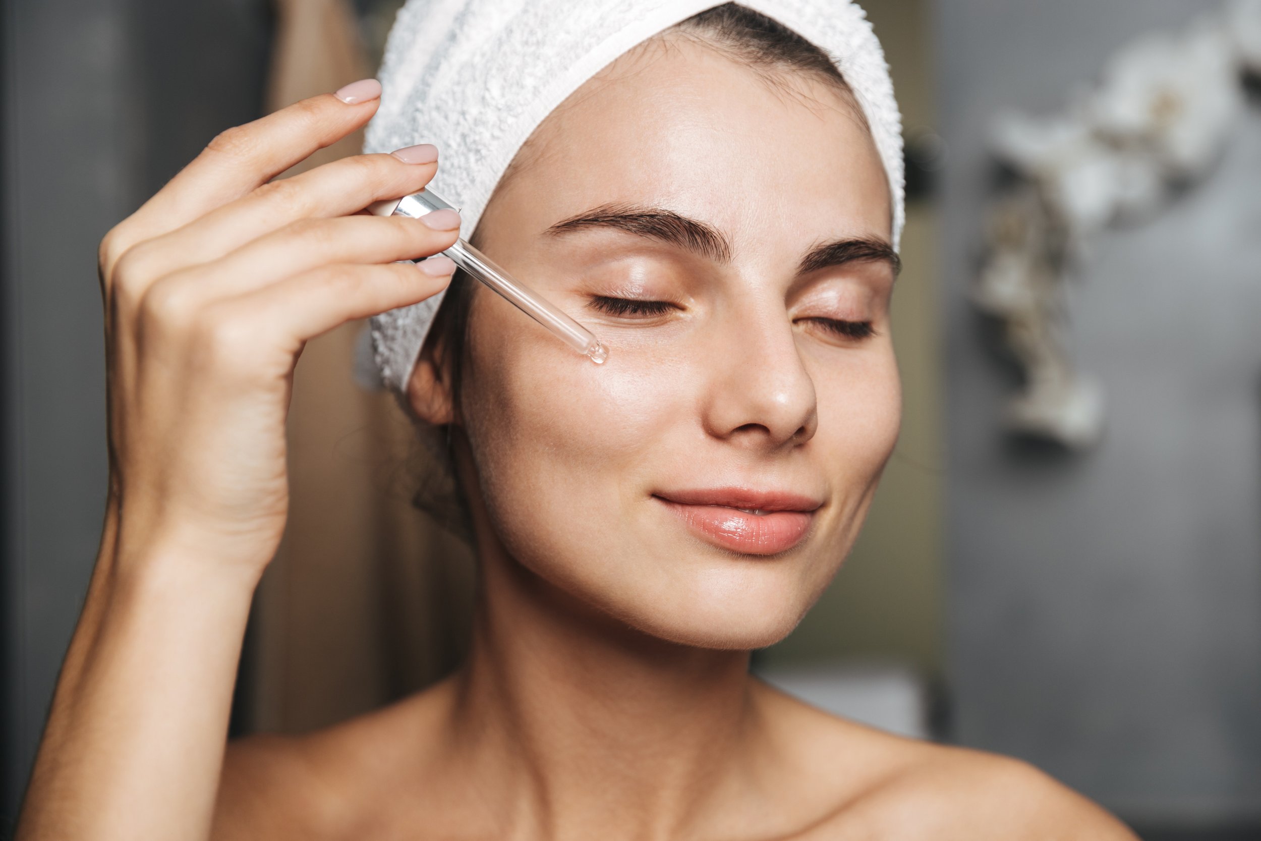 Woman applying face serum to cheek