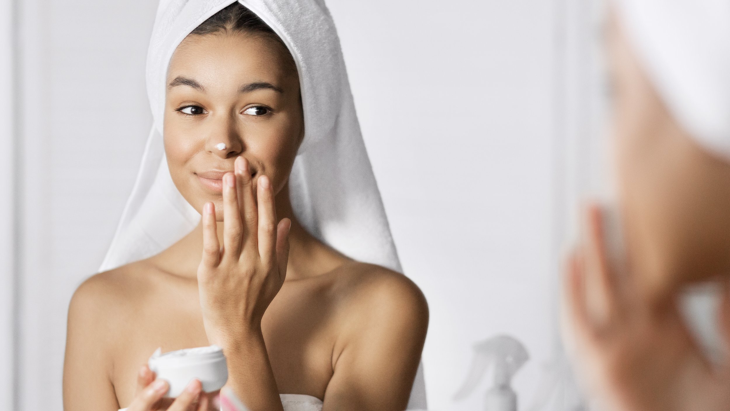 Woman dabbing lotion on her nose after a shower