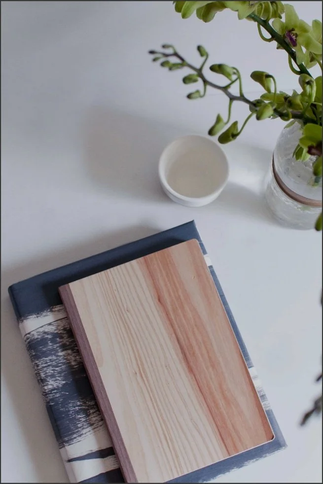 Journals and a small vase of green orchids on a white table