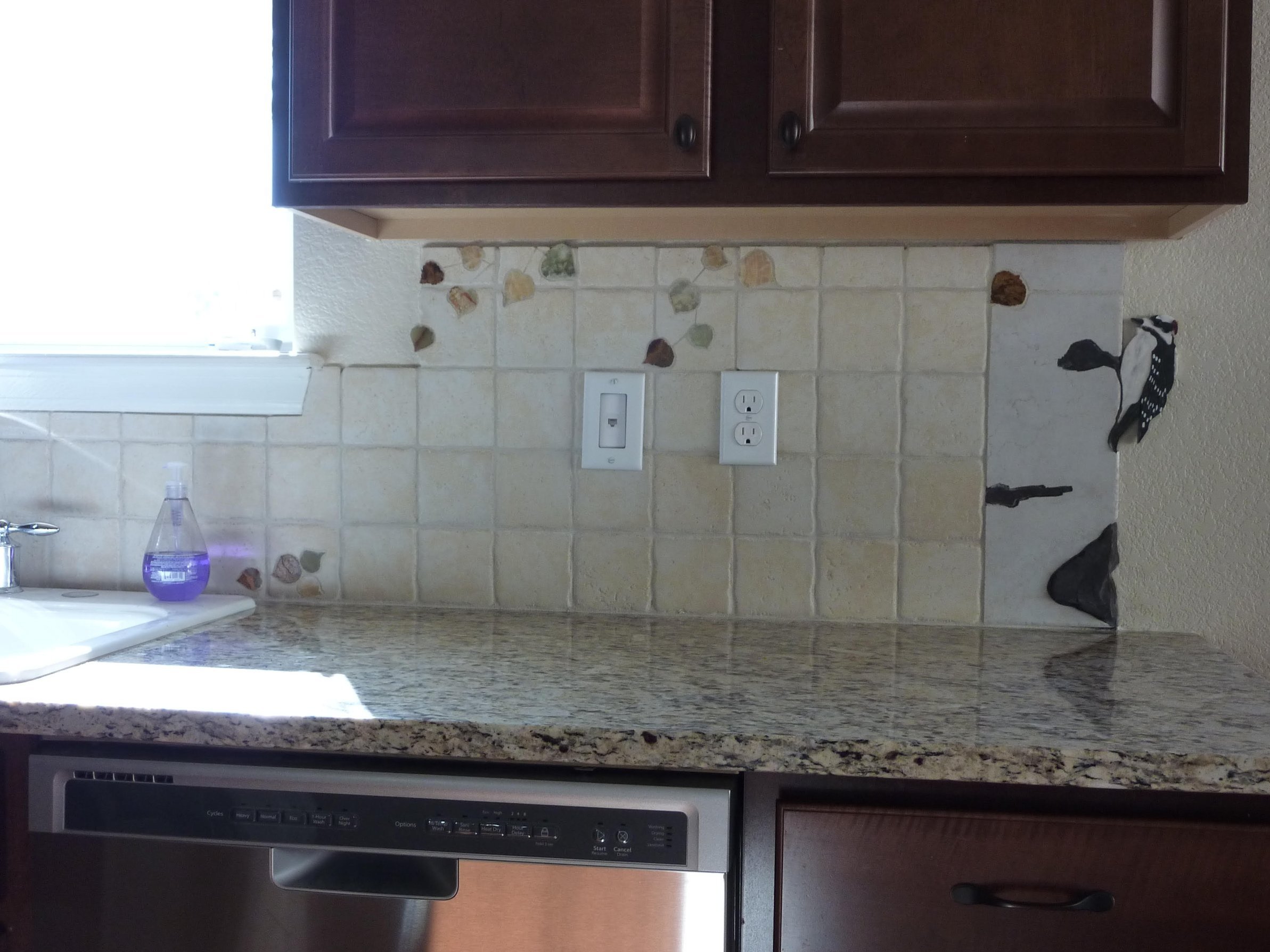 The downy woodpecker, so common in Colorado, clings to the aspen tree at the right.
All trees and aspen leaves are inlaid in the 4" x 4" travertine tiles to achieve a smooth, clean fit.