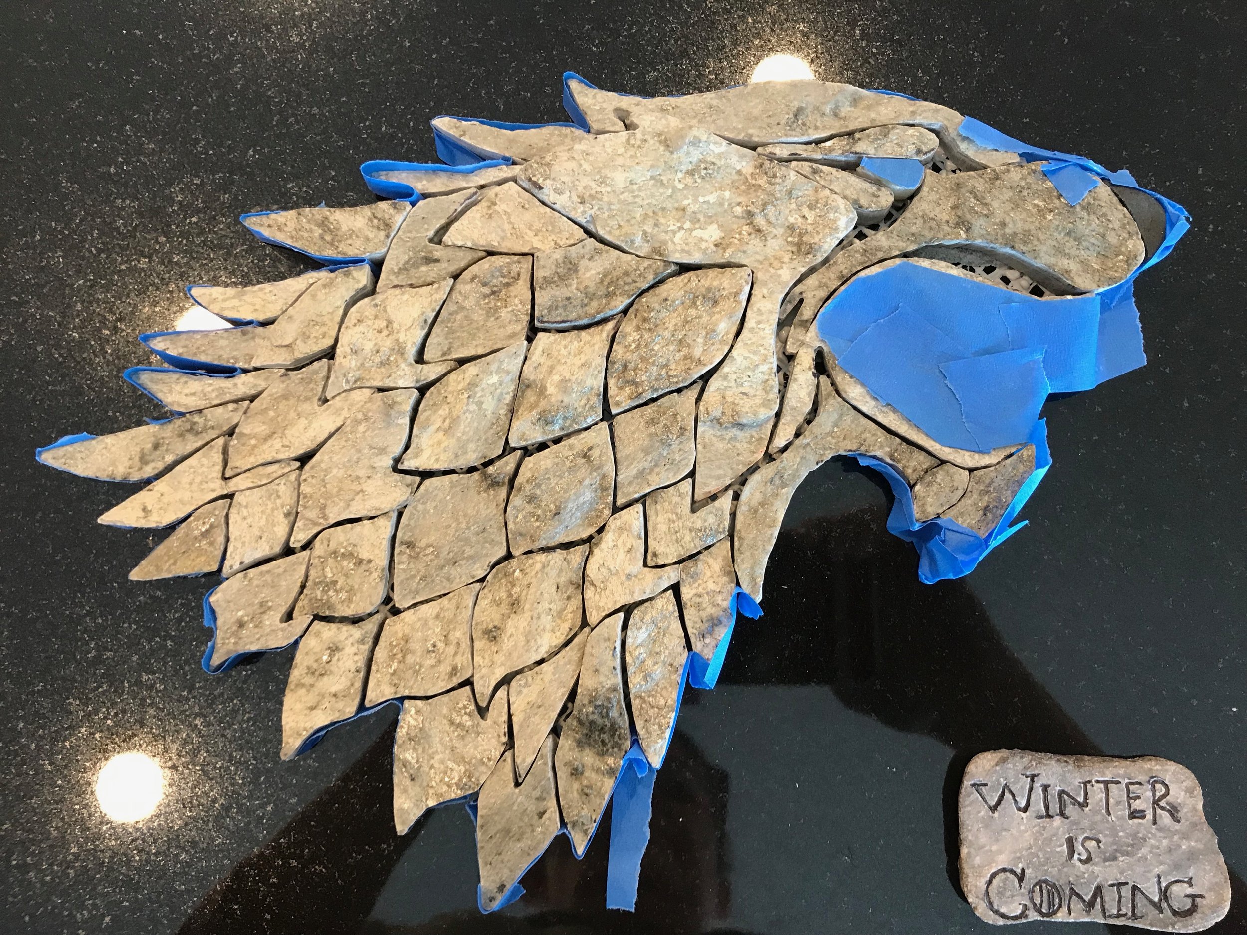 Taped off sections in preparation of grouting.
Complete with the house Stark motto, ‘Winter is Coming’, meticulously hand-carved into rock. next, the entire piece will be sealed with a high-quality stone sealer, and the artist’s signature ladybug g