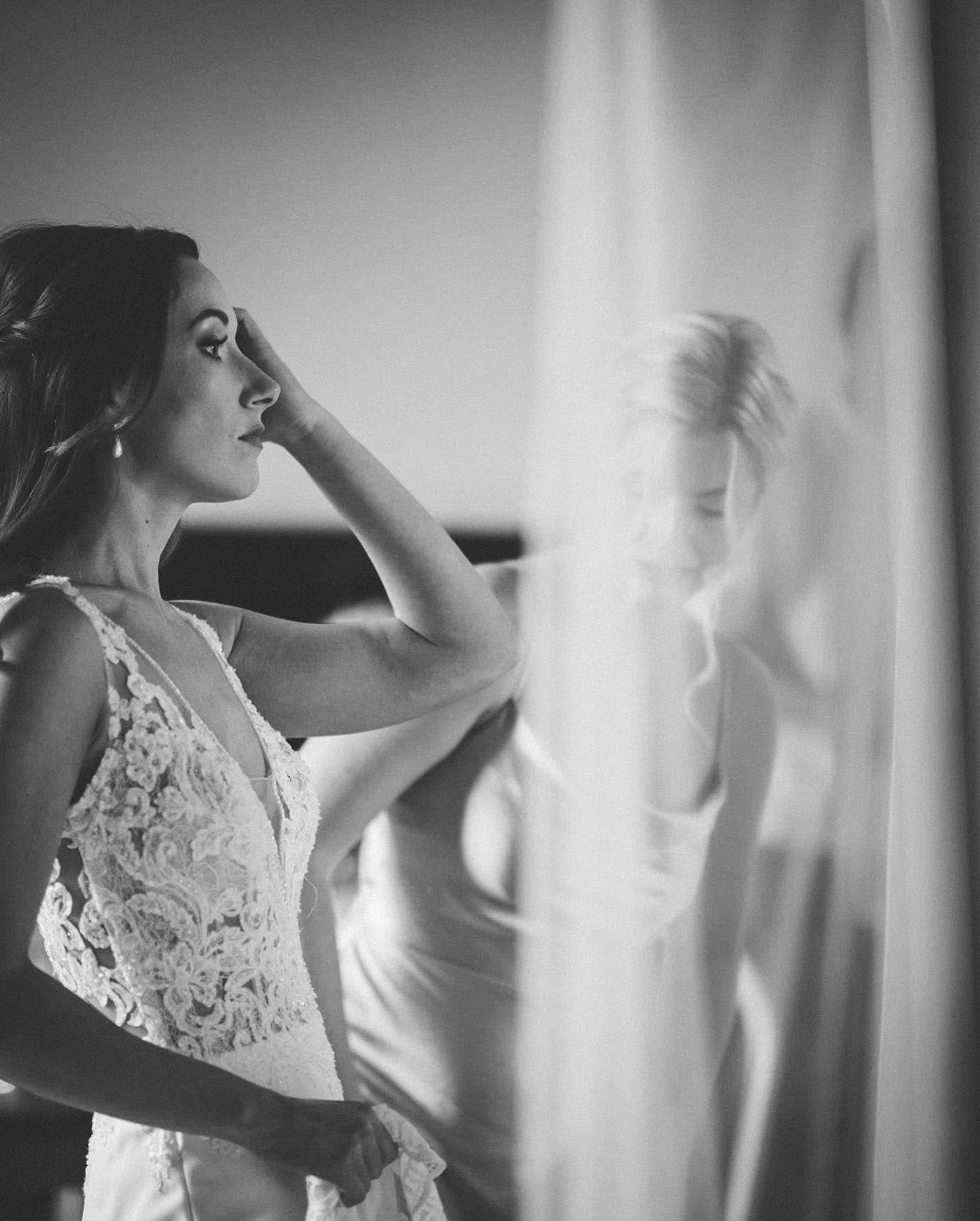 black and white photo of a bride getting ready, looking into a mirror