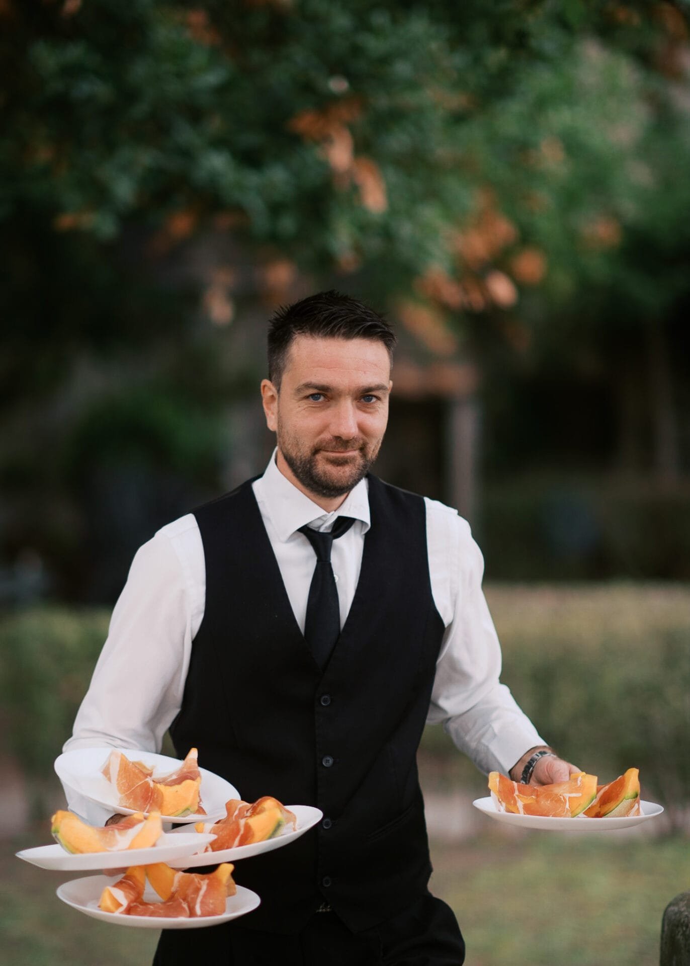 italian waiter serving dinner at an outdoor wedding reception