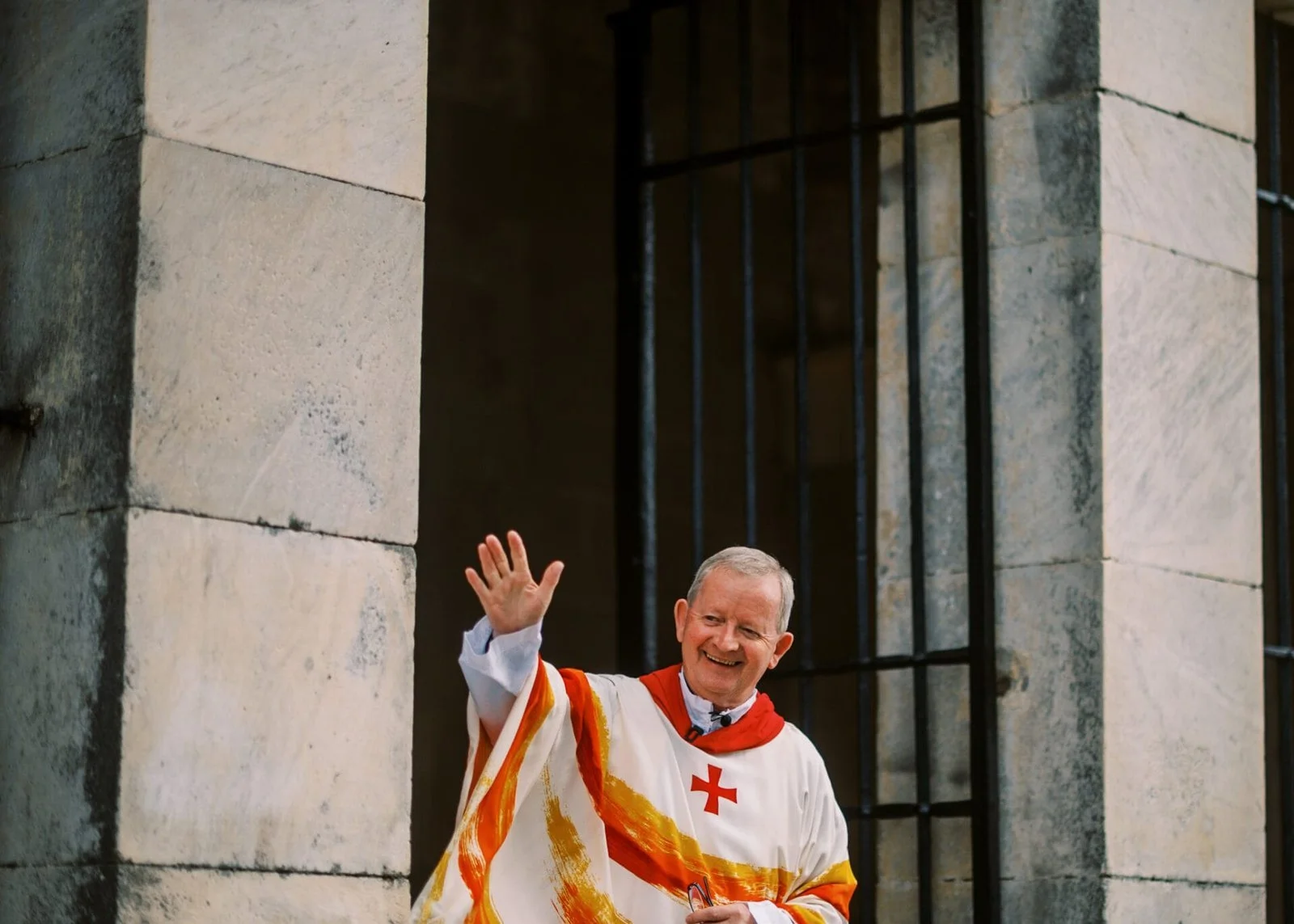 a catholic priest waving amd smiling before a Destination Wedding in Rome