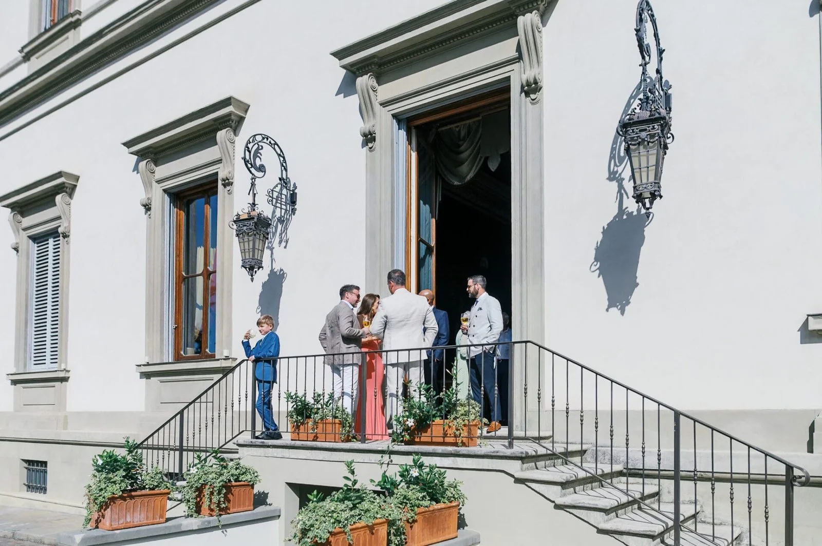 Destination Wedding. people congragating in the sunshine on a balcony at Villa Cora Florence