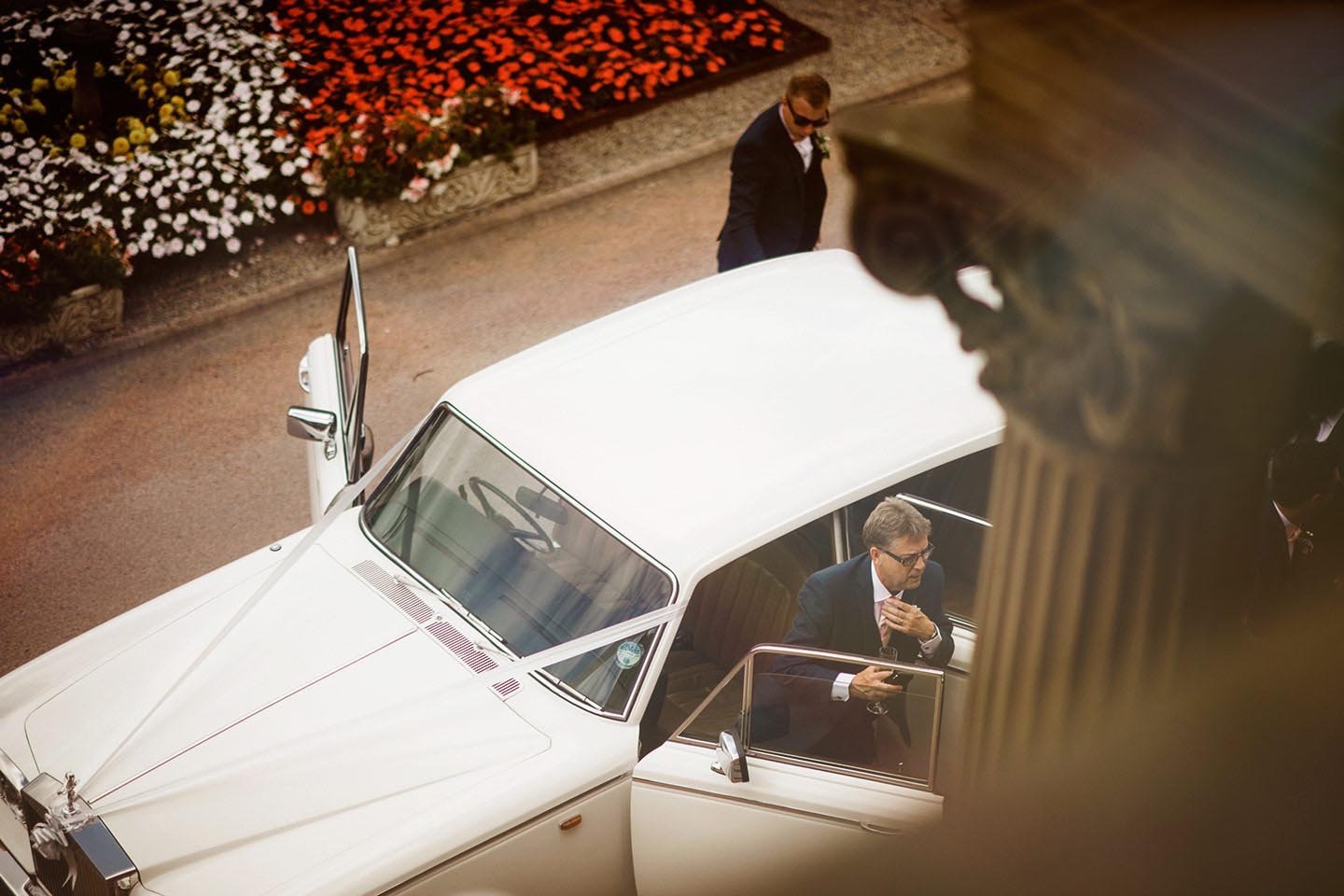 Men in suits with sunglasses around a vintage white car. Oulton Hall Leeds Wedding day