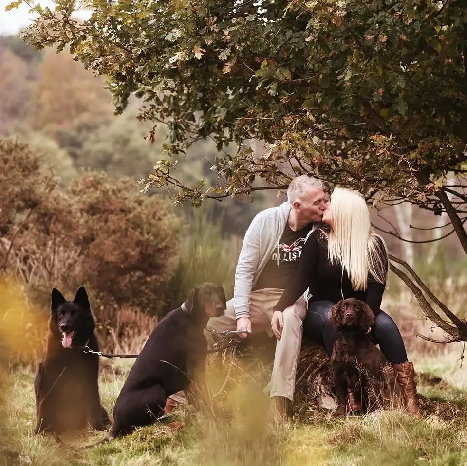 Couple sitting on a log with their Dobermann, German Shepherd, and Spaniel in Clumber park on a pre-wedding photoshoot