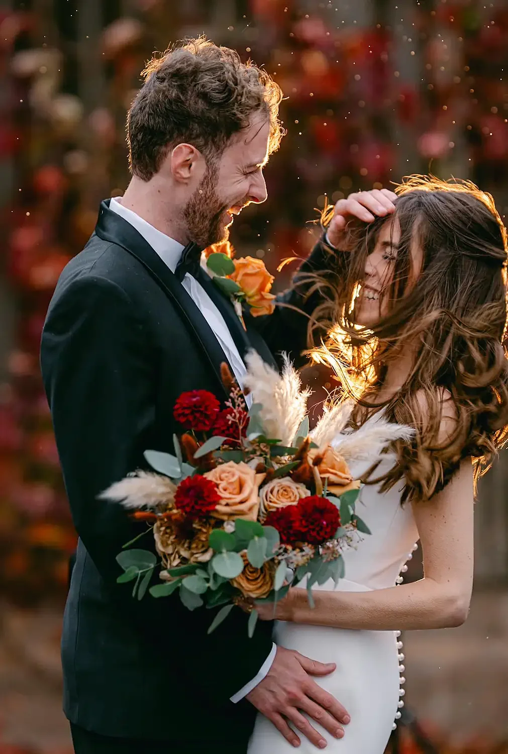 bride and groom laughing during a windy and rainy photo during autoum at hodsock priory