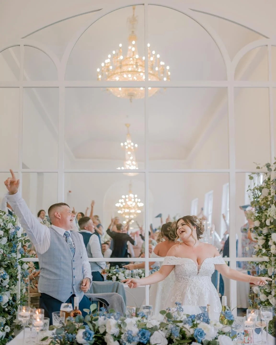 A bride and groom dancing at their wedding reception, surrounded by guests, floral decorations, and chandeliers in a bright, elegant venue. Norwood Park wedding photographer