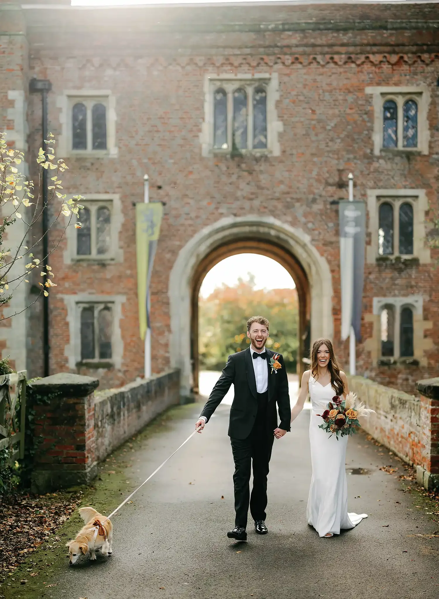 bride and groom laughing holding hands with their pet dog on their wedding day. At hodsock priory