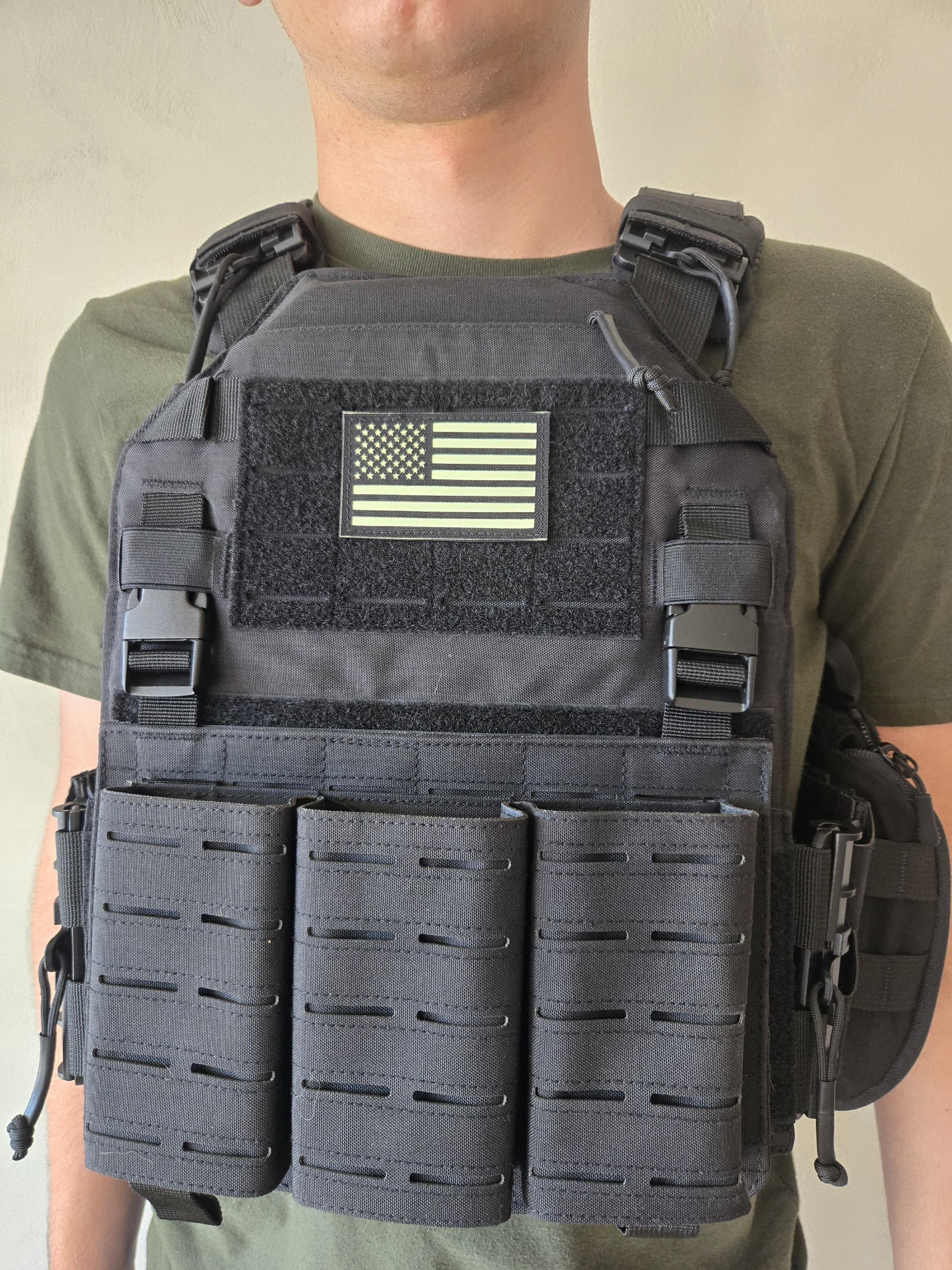 Front view of black tactical plate carrier with American flag patch and MOLLE pouches