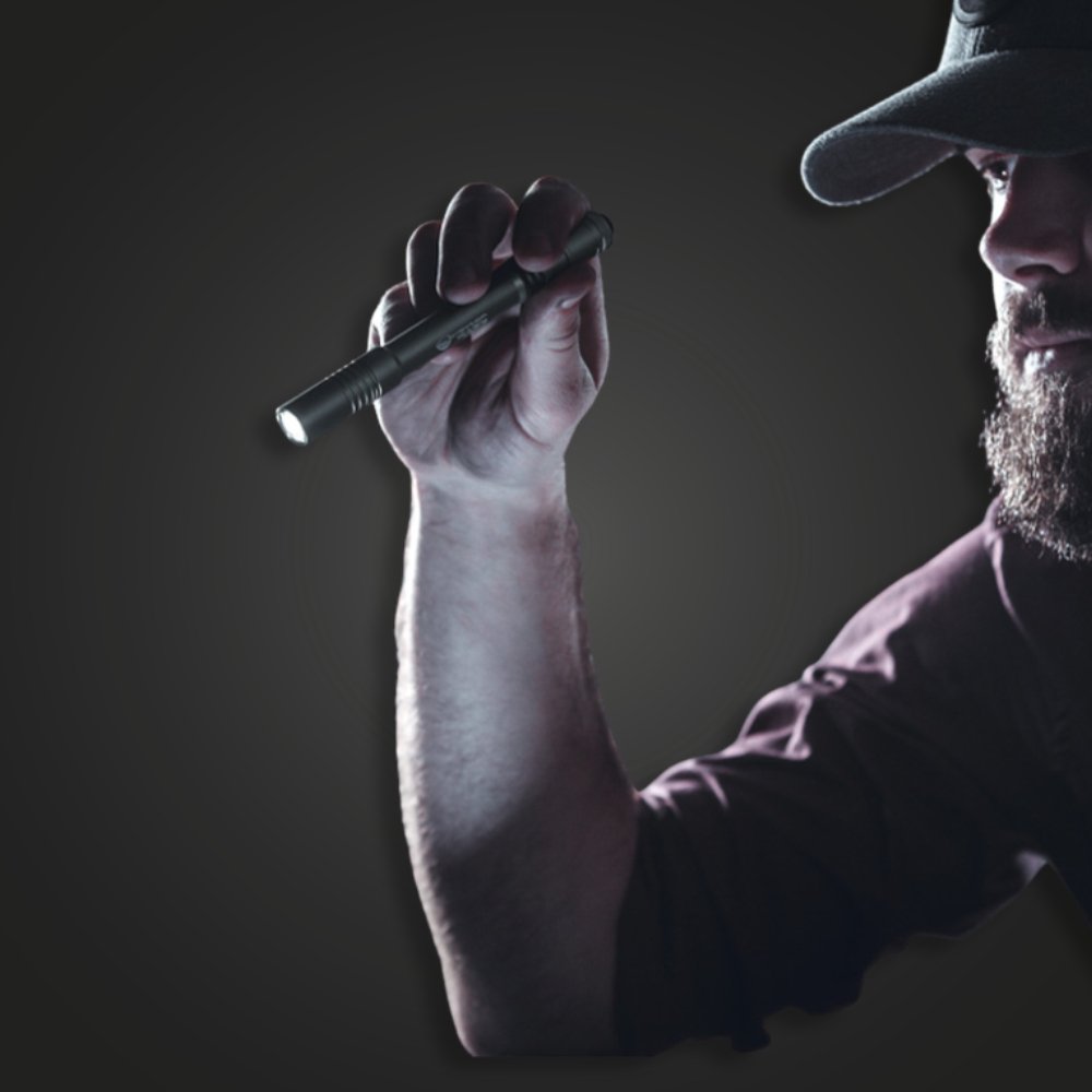 Man in a cap holding a lit Streamlight Stylus Pro penlight in one hand