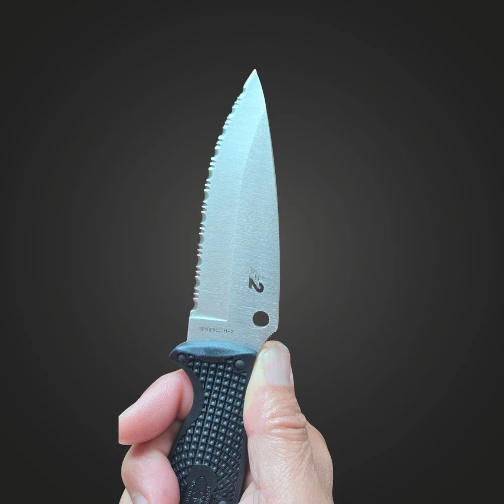 Spyderco Jumpmaster 2 held upright, showing the H-2 steel stamp and serrated edge