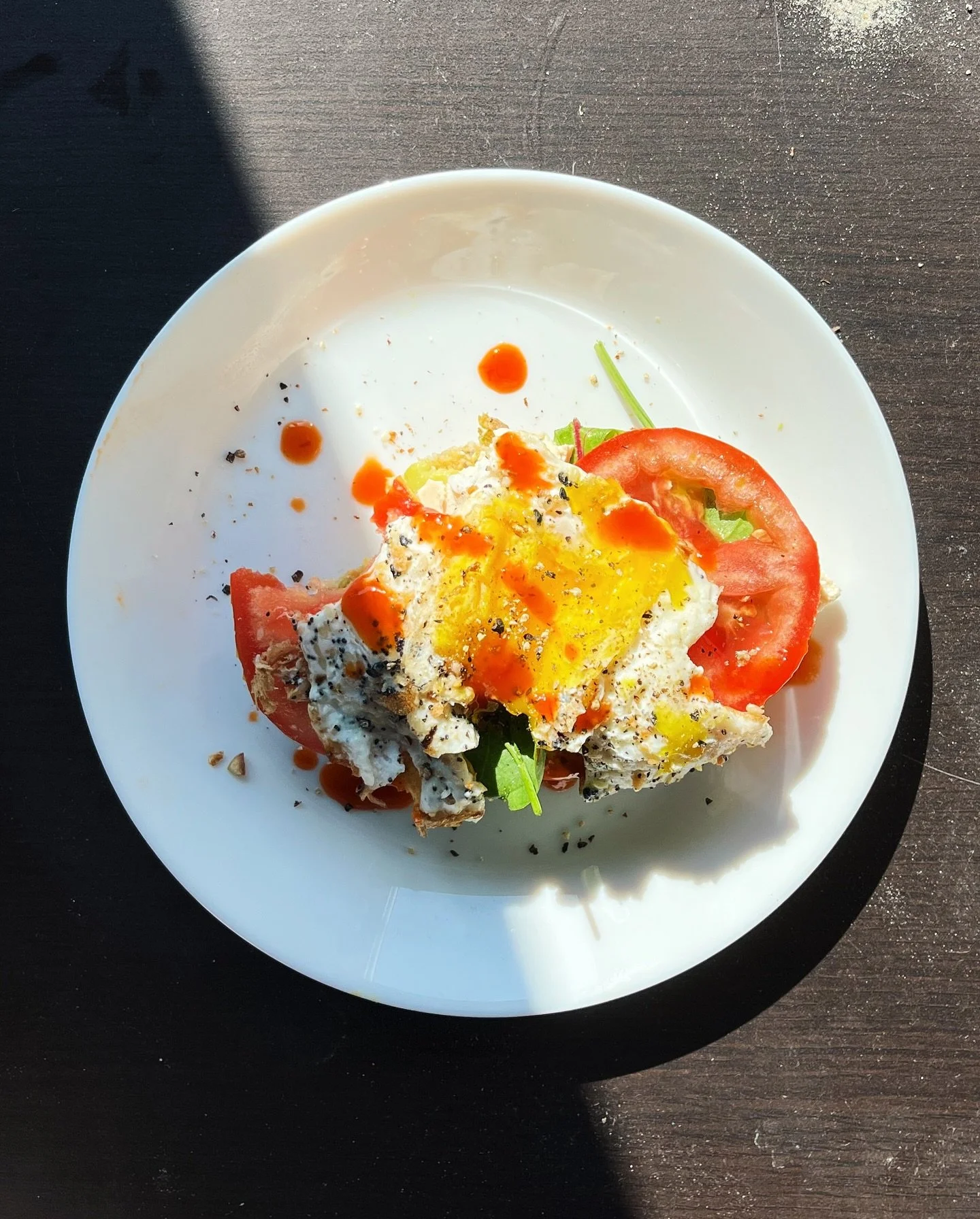 a classic 👩&zwj;🎨

A slightly botched fried egg over top a thick sliced tomato and arugula. Smattered with black pepper and hot sauce!