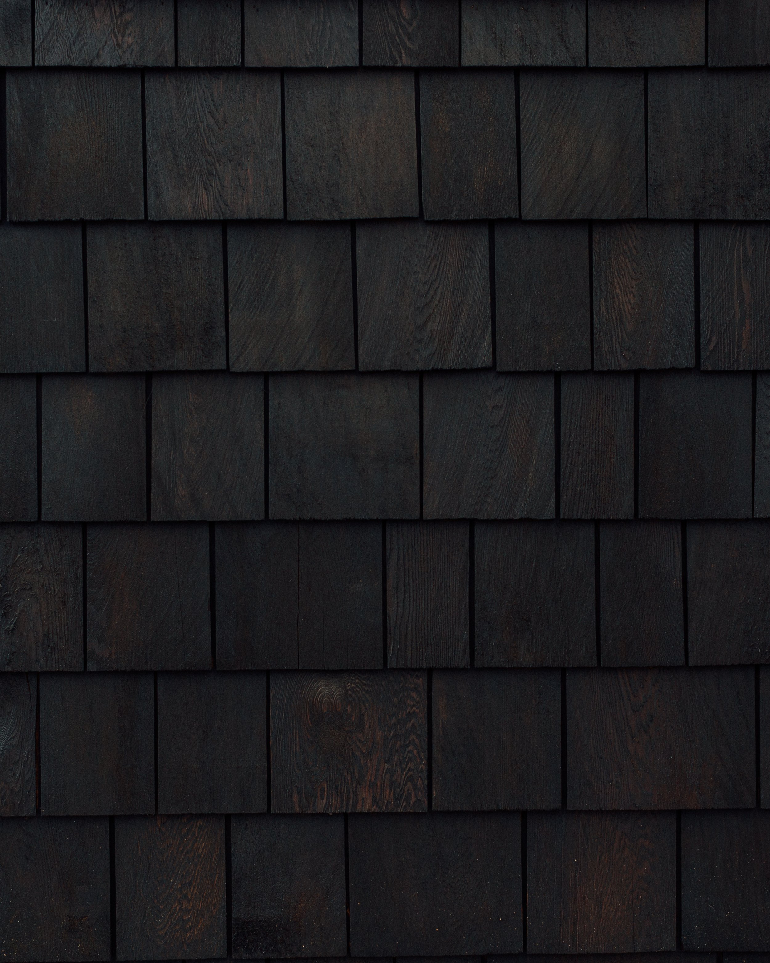 Close-up view of black wooden shingles on a building's exterior wall.