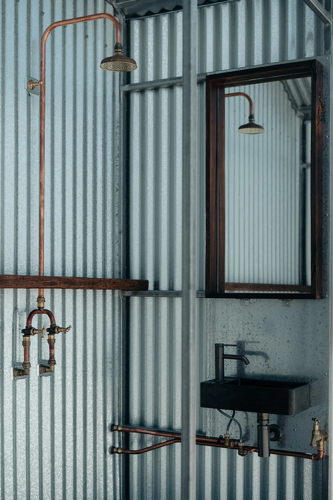 A black wooden wall with a gold-colored sign that reads "Harbor Saunas". The wall is made of horizontal planks, and there are some pieces of snow on the wooden surface below.