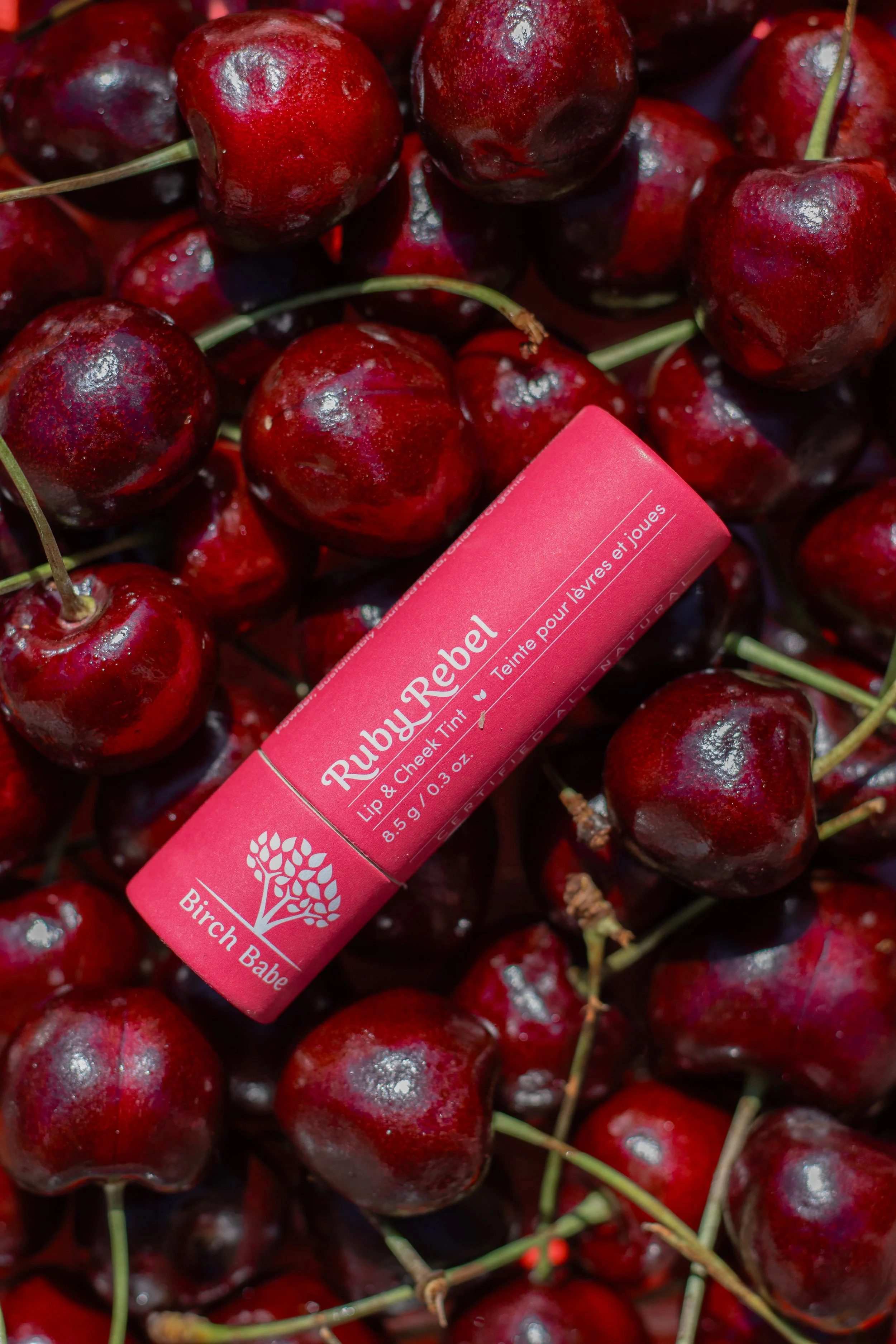 Lip and cheek tint styled among fresh cherries for a beauty client.