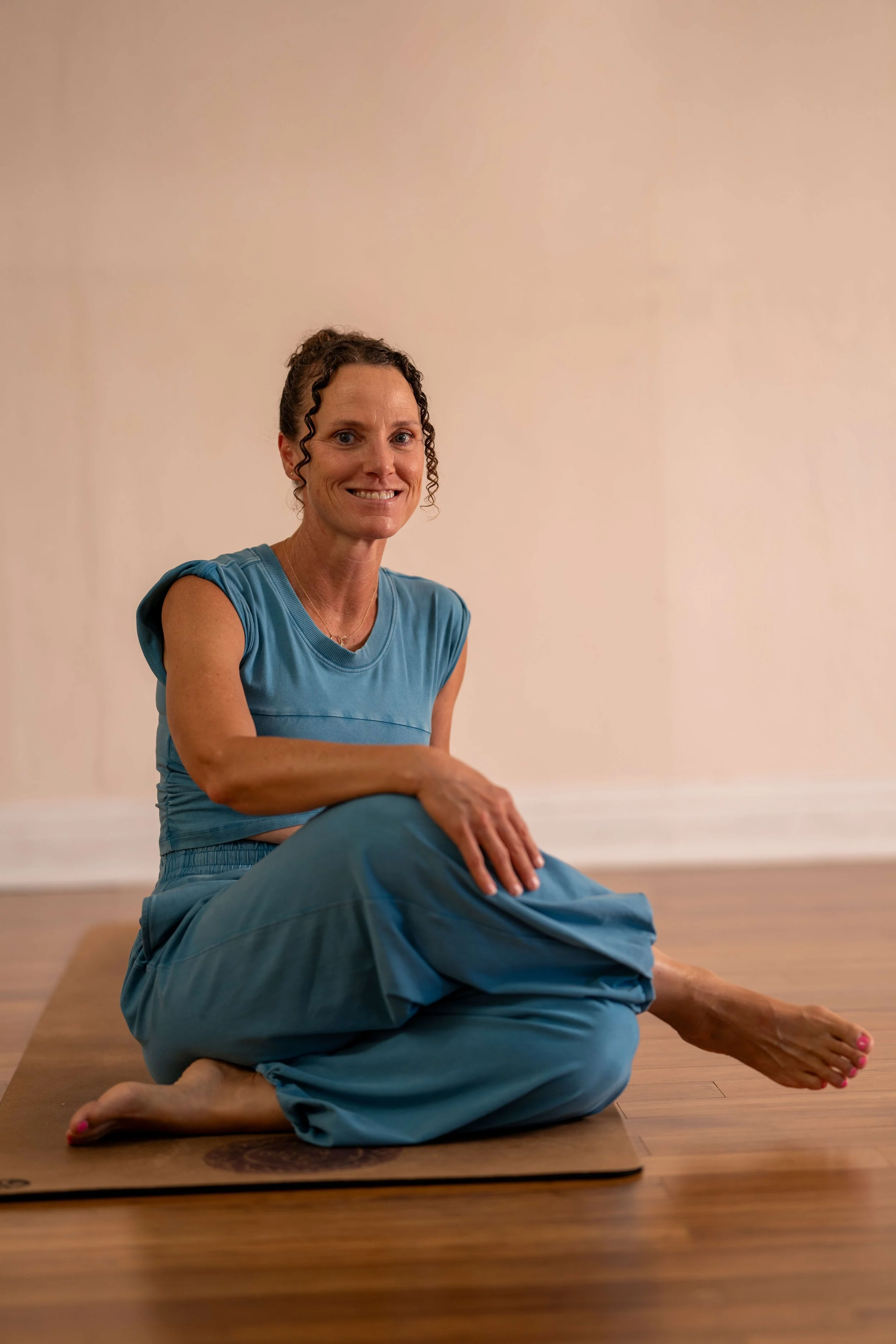 Yoga instructor Carmen guiding students through a mindful yoga class, combining flowing asana, breathwork, and meditation to cultivate strength, serenity, and self-awareness