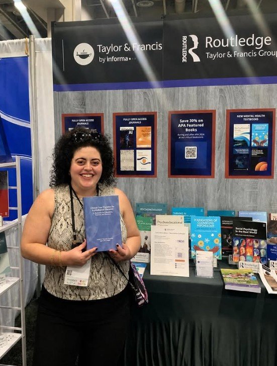 Dr. Regueiro at the APA convention, with her newest publication at the Routledge booth (2026)