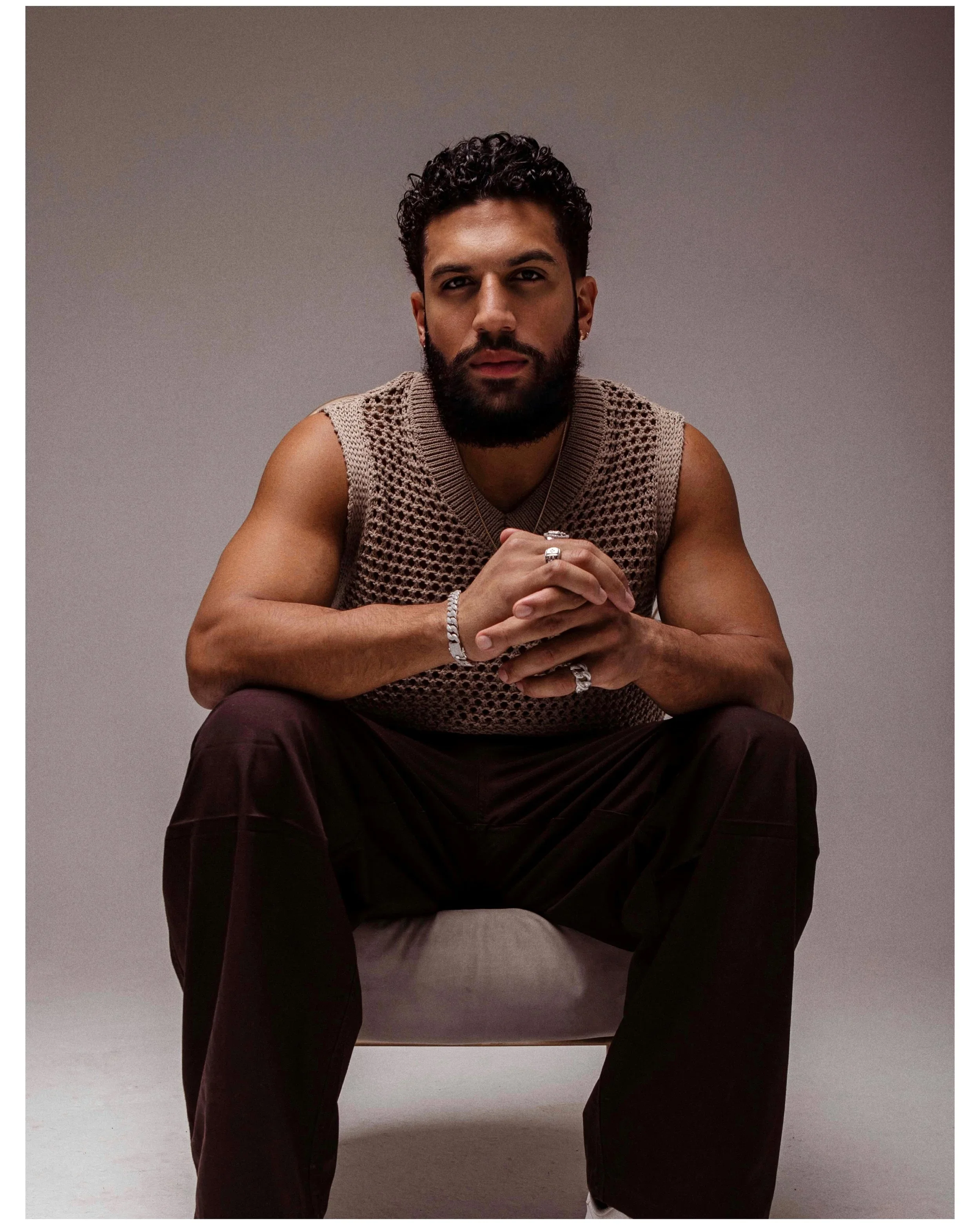 Official portrait of Dominican bachata artist Nandy Versátil, seated in a knit top