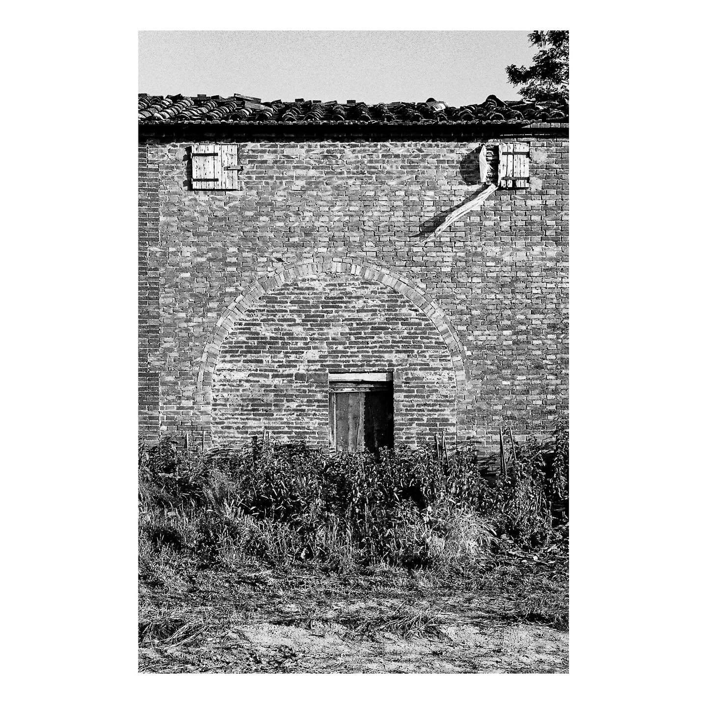 The combination of very small shuttered openings at the upper level and the partial cover of the ground floor door makes it difficult to get a sense of human scale. 

At some point, this farm building in Bettolle near Siena benefitted from a much lar