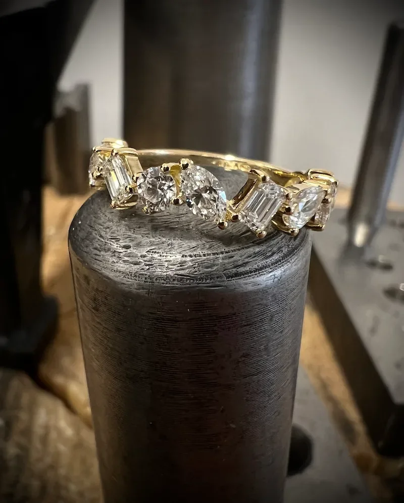 Ein Memoire-Ring mit verschiedenen fancy cut Diamanten, auf einem Amboss.