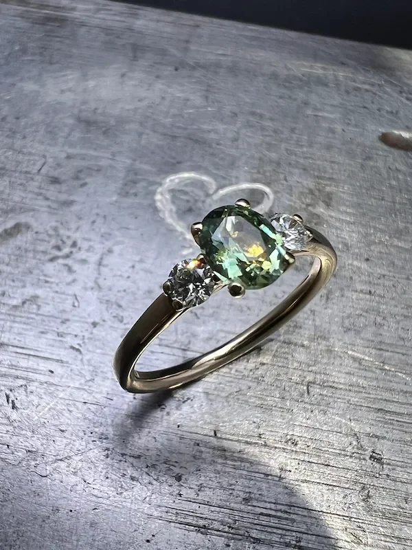Verlobungsring Gelbgold mit grünem Saphir und Diamanten.