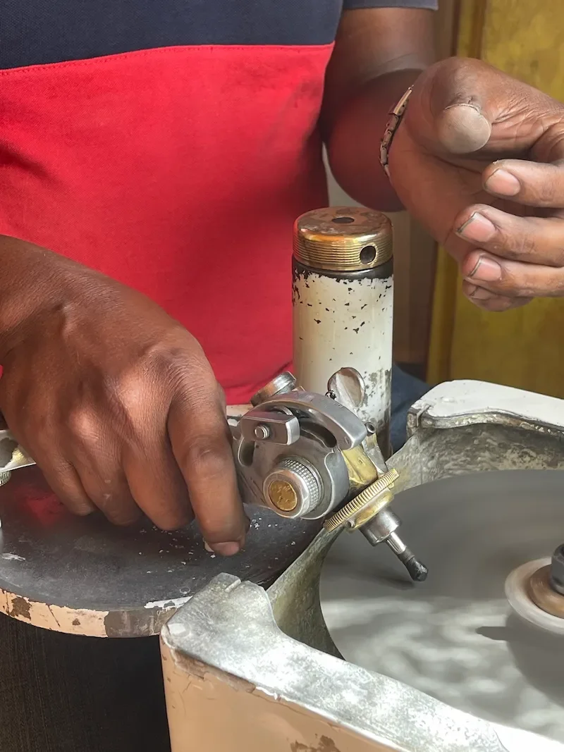 Edelsteinschleifer bei der präzisen Bearbeitung eines Saphirs an der Schleifscheibe