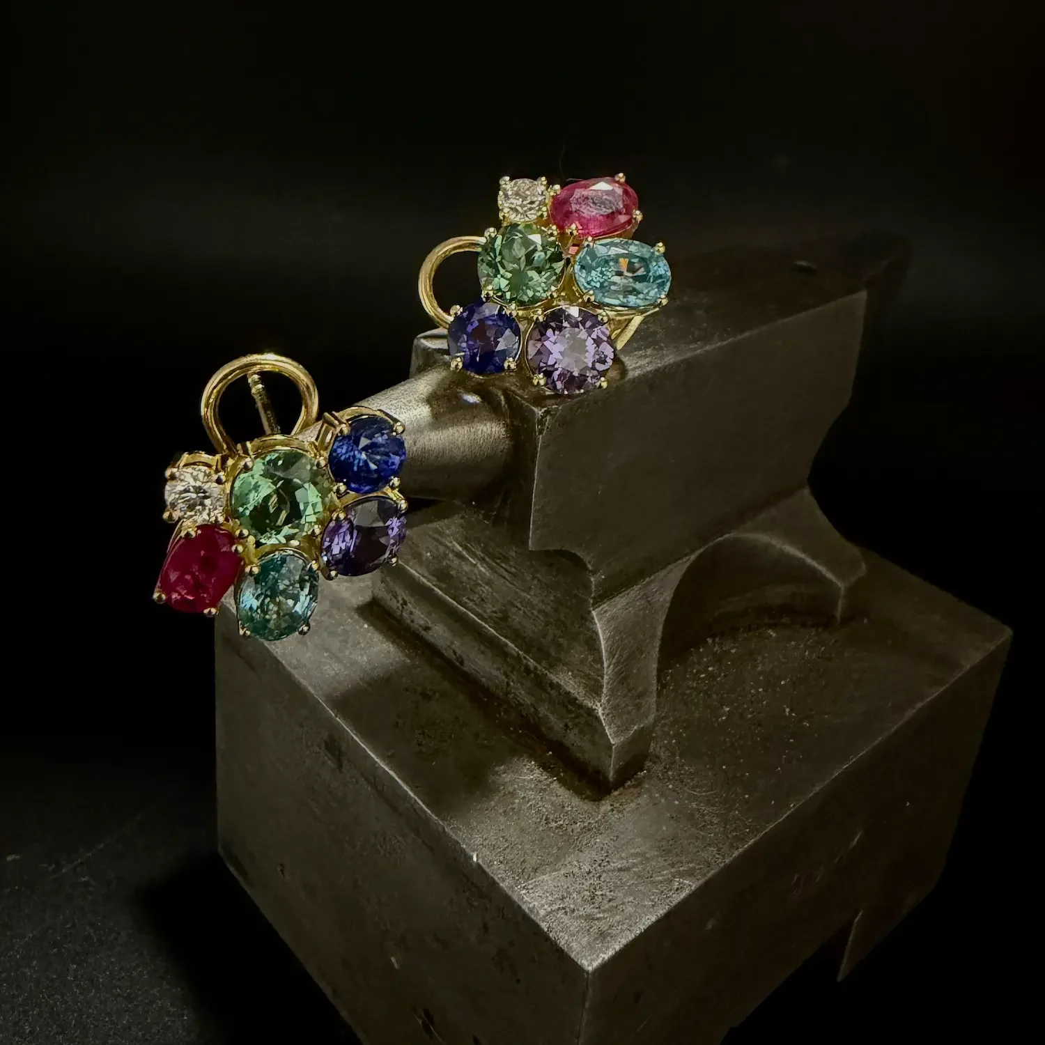 Ohrstecker mit verschieden bunten Edelsteine auf einem Amboss