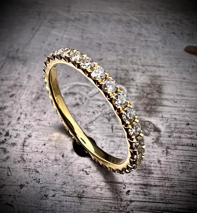 Goldring mit verbundenen Diamanten auf einer Holzoberfläche