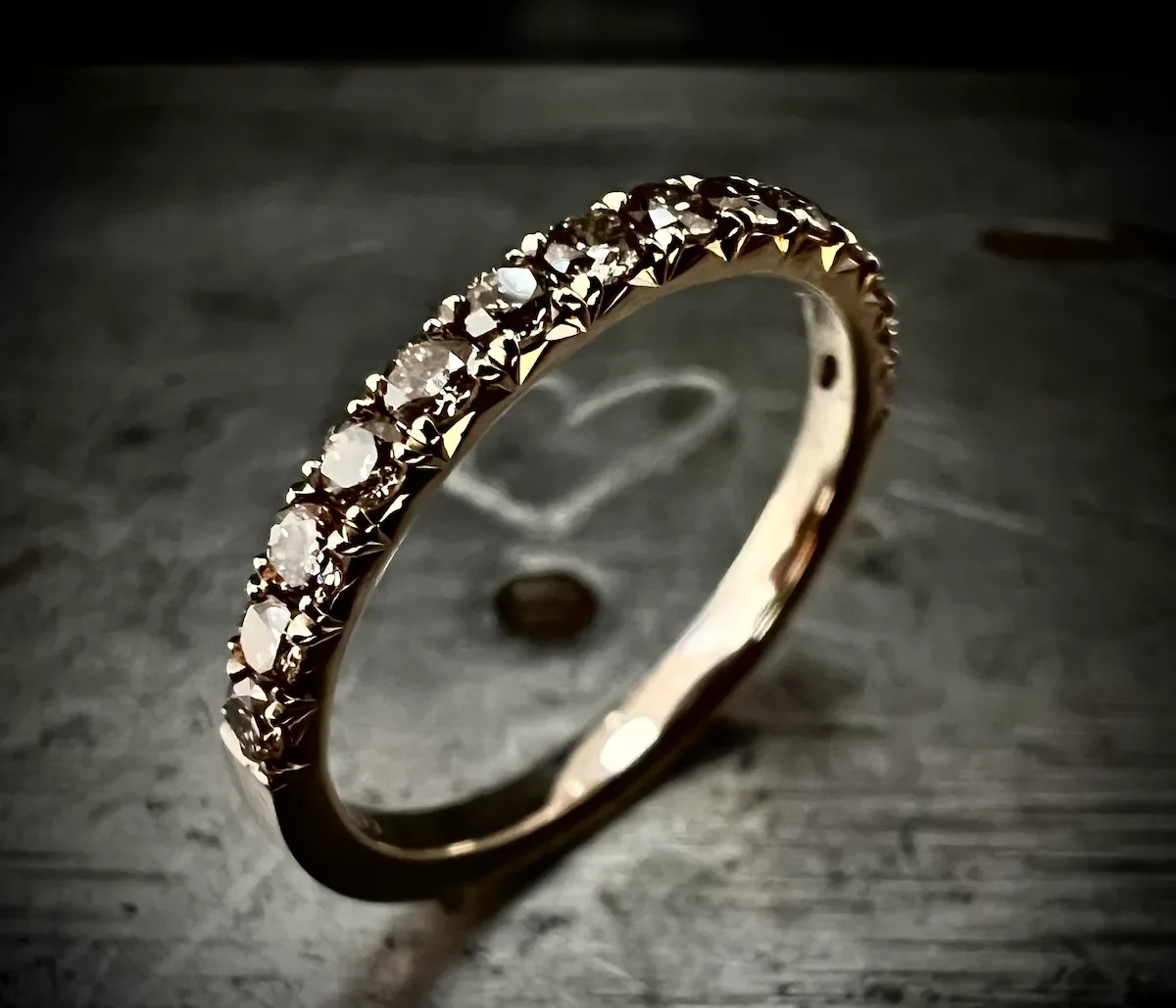 Goldring mit eingelassenen kleinen Diamanten auf dunklem Hintergrund