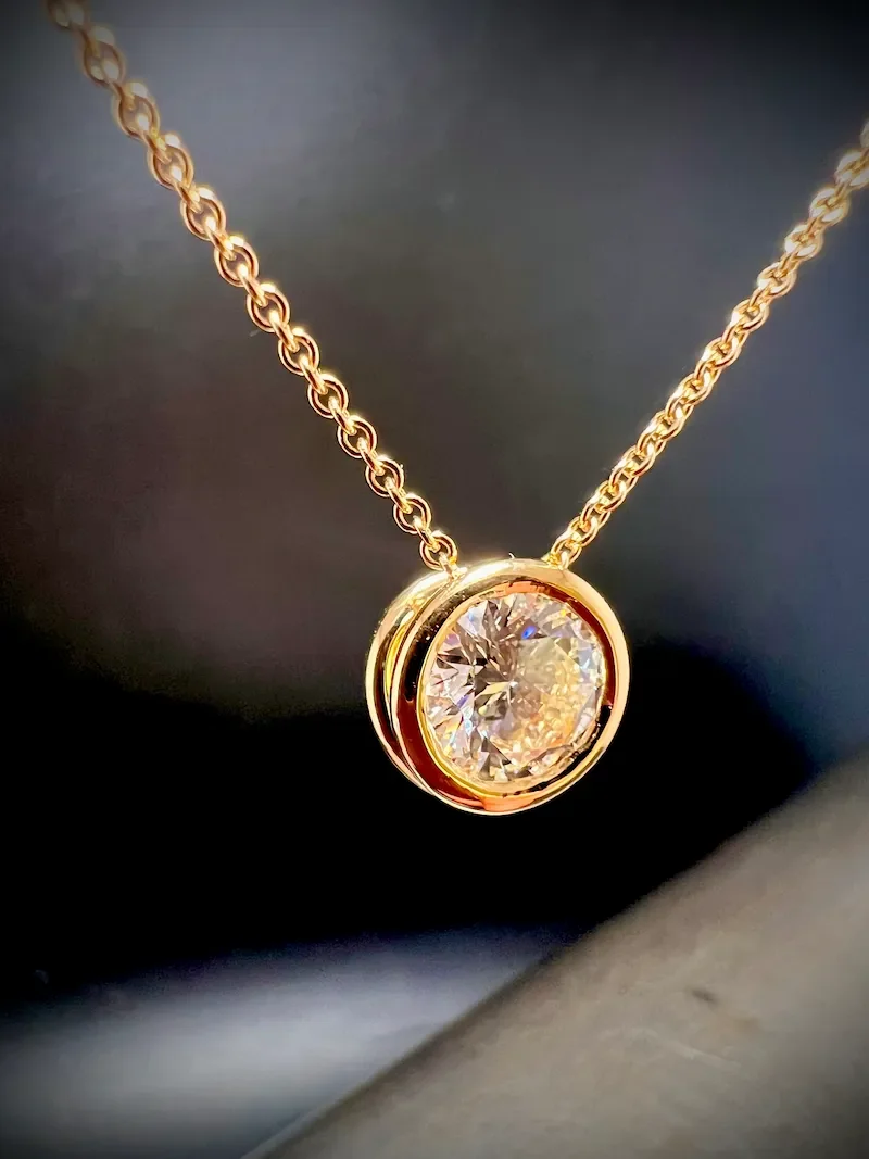 Goldene Halskette mit einem großen runden Diamanten als Anhänger.