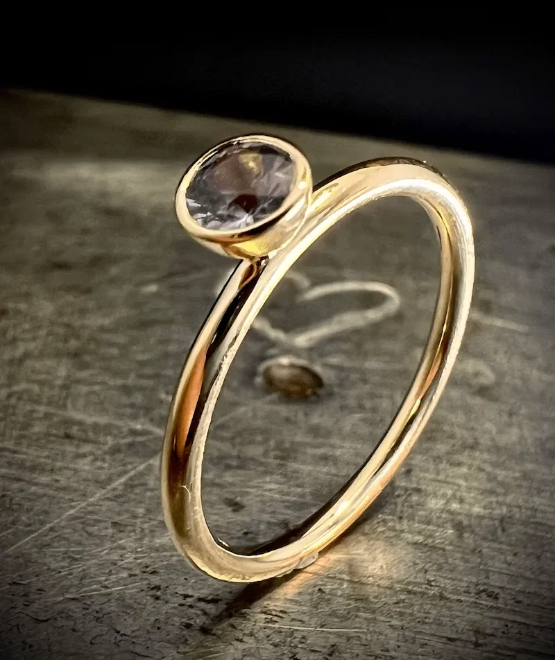 Goldring mit rundem Saphir in einer Zargenfassung, die auf der Ringschiene sitzt