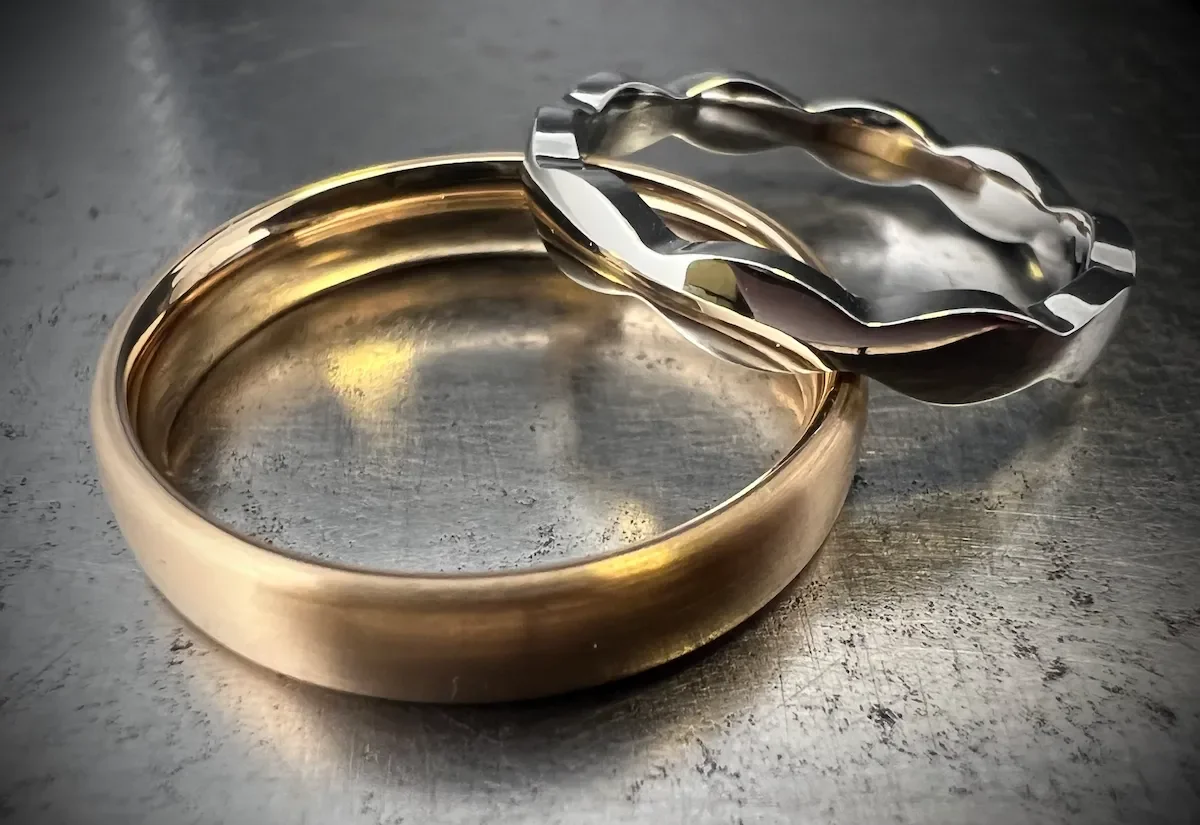 Zwei goldene und silberne Ringe aus Metall auf einer Metalloberfläche.