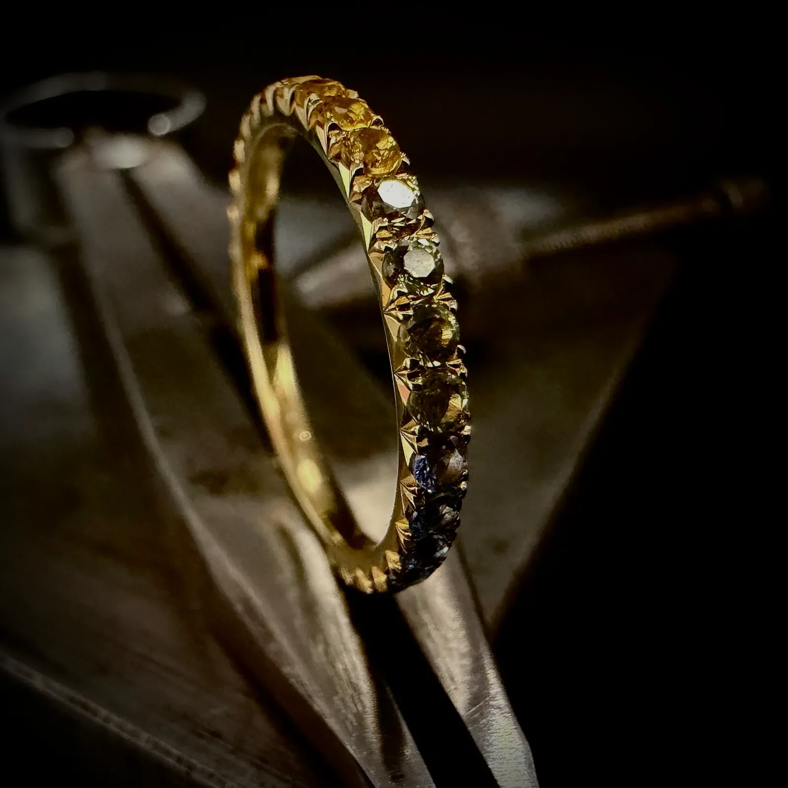 Goldene Ring mit schwarzen und klaren Edelsteinen, auf einer dunklen Holzoberfläche