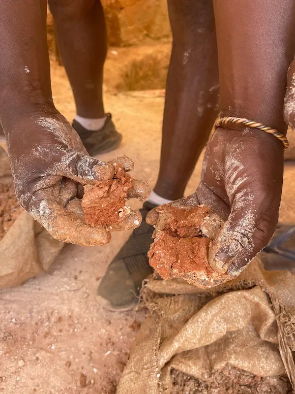 Bergbau von Edelsteinen in Madagskar: Hände halten rohe Erde bei der Gewinnung für Miadana und die Isarschmiede