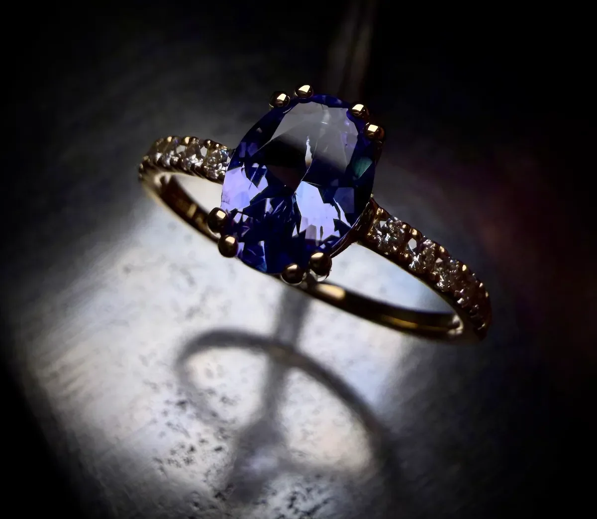 Handgefertigter Verlobungsring mit einem großen, ovalen Tansanit in kräftigem Blau-Violett, gefasst in Gelbgold mit einer diamantbesetzten Ringschiene (Mémoire-Stil).