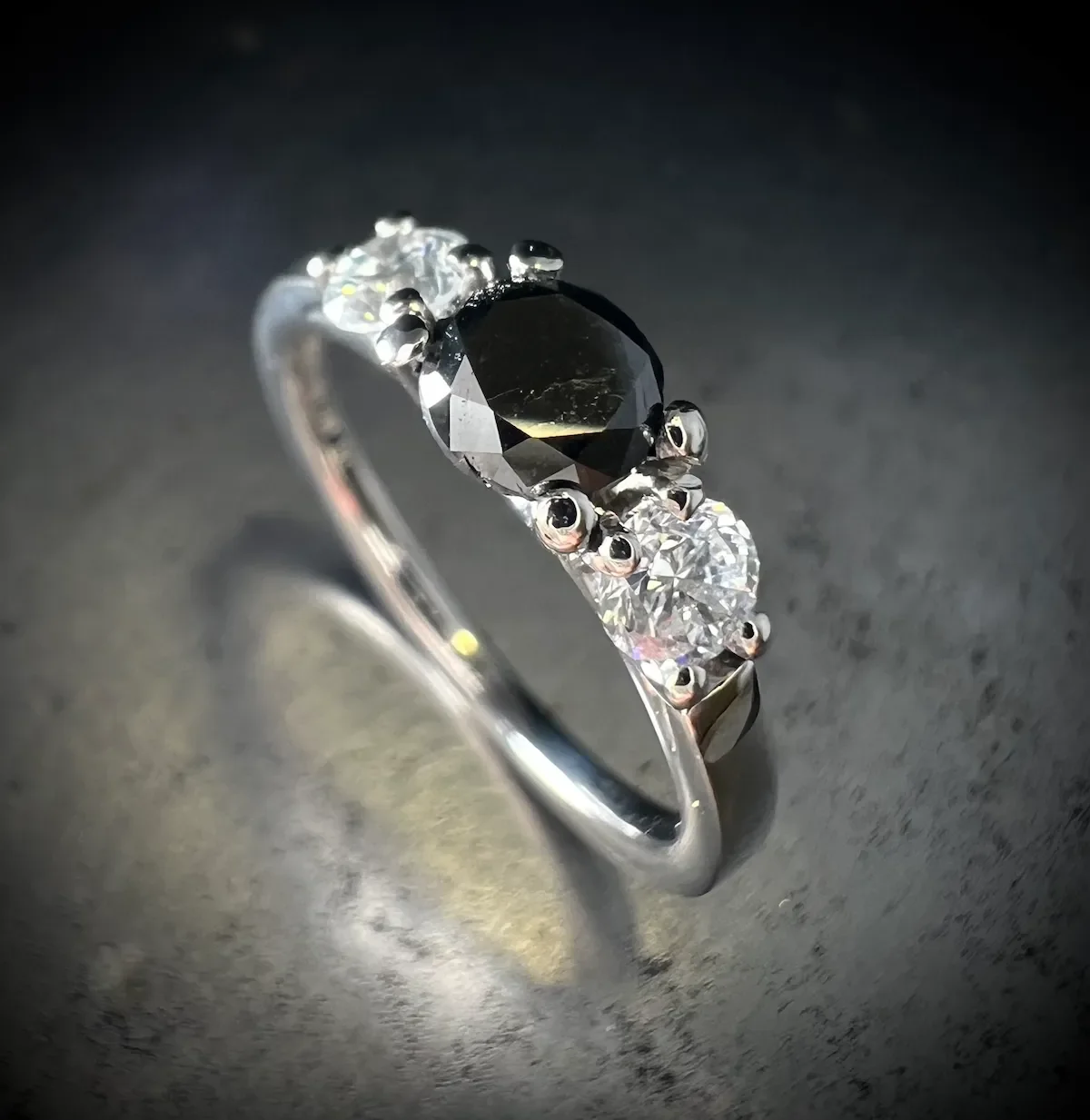 Trilogie-Ring mit schwarzem Hauptdiamanten und zwei weißen Diamanten in Weißgold, Isarschmiede München.