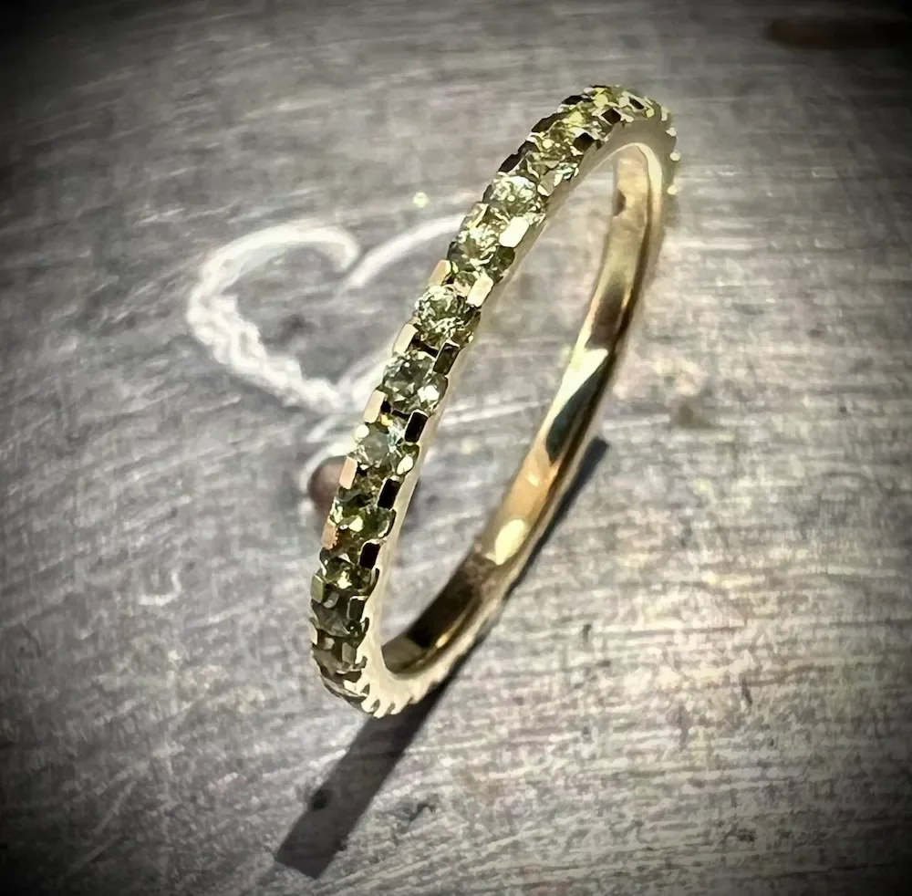 Goldring mit kleinen Diamanten auf einem dunklen Holzuntergrund, Schatten in Herzform