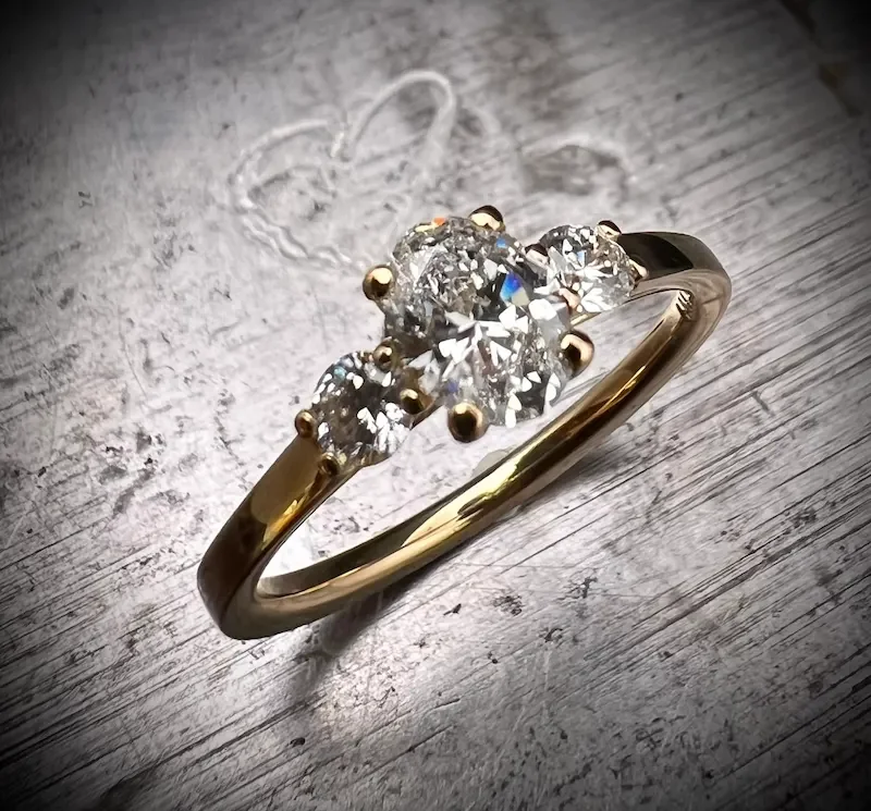 Trilogie Verlobungsring aus Gelbgold mit ovalem Hauptdiamanten und zwei seitlichen Diamanten, München.