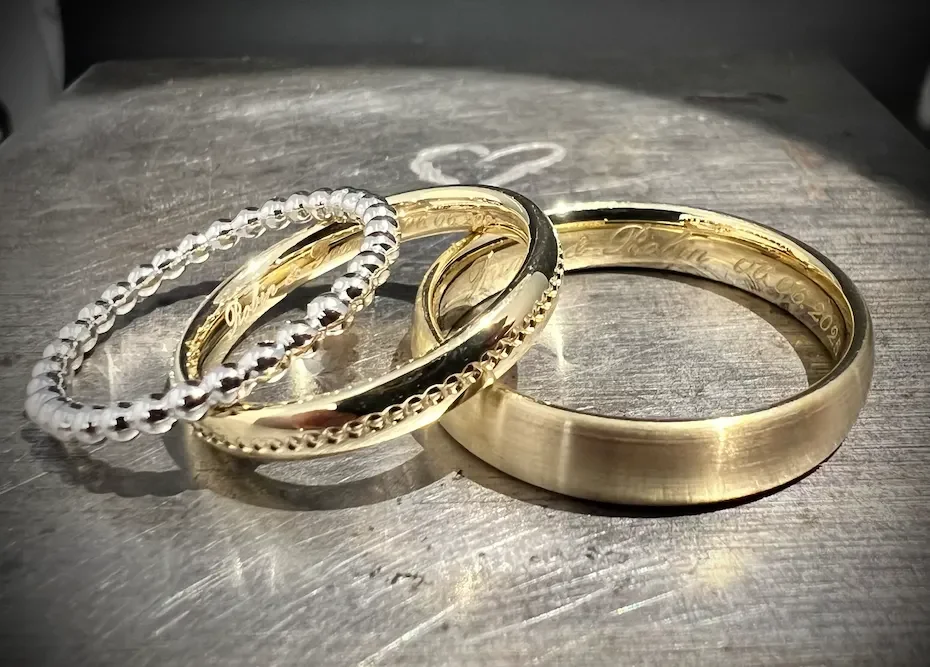 Vier goldene und silberne Eheringe auf einem Holzoberfläche.